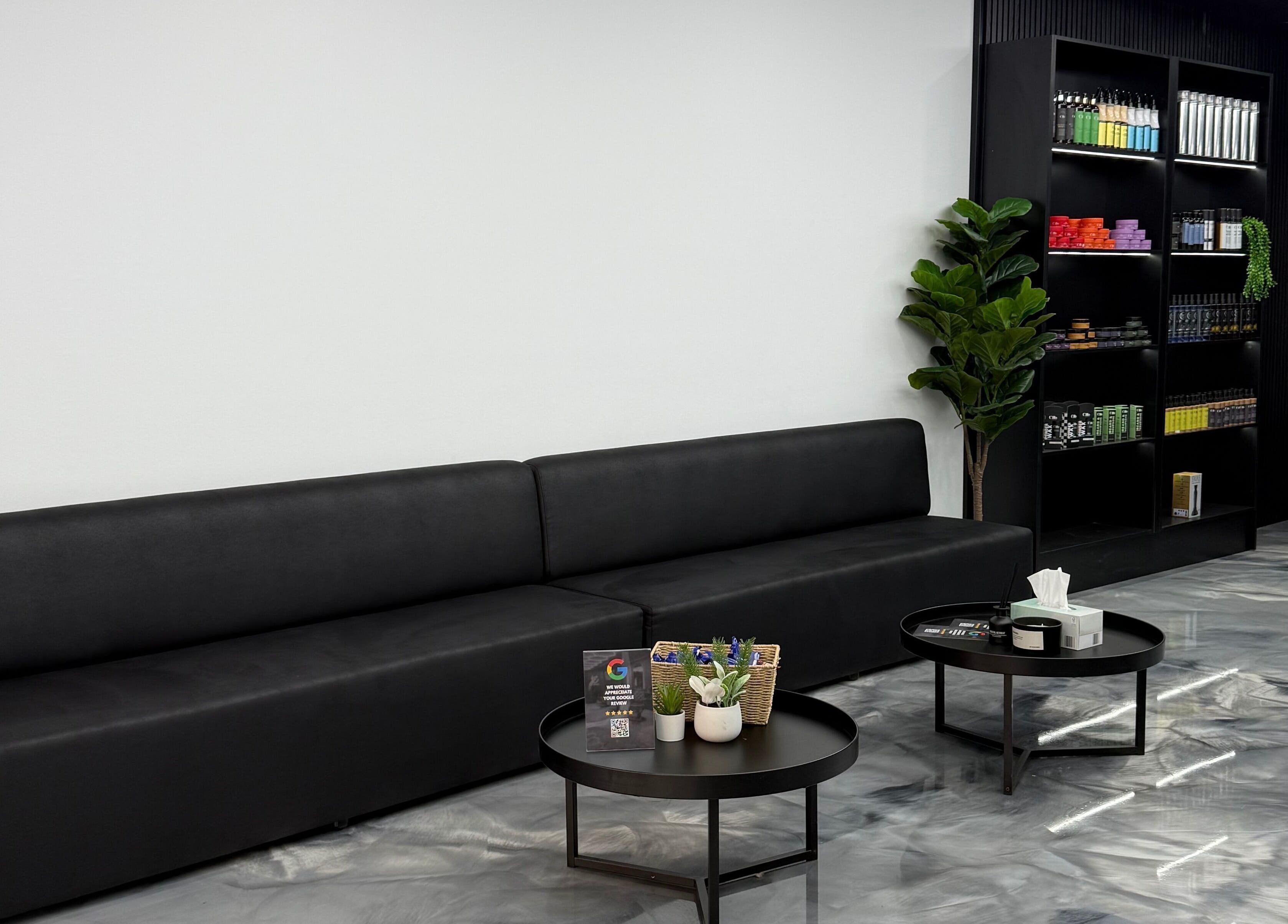 Stylish waiting area at JE Barbers, Melbourne, Victoria, AU with sleek black seating and modern decor.