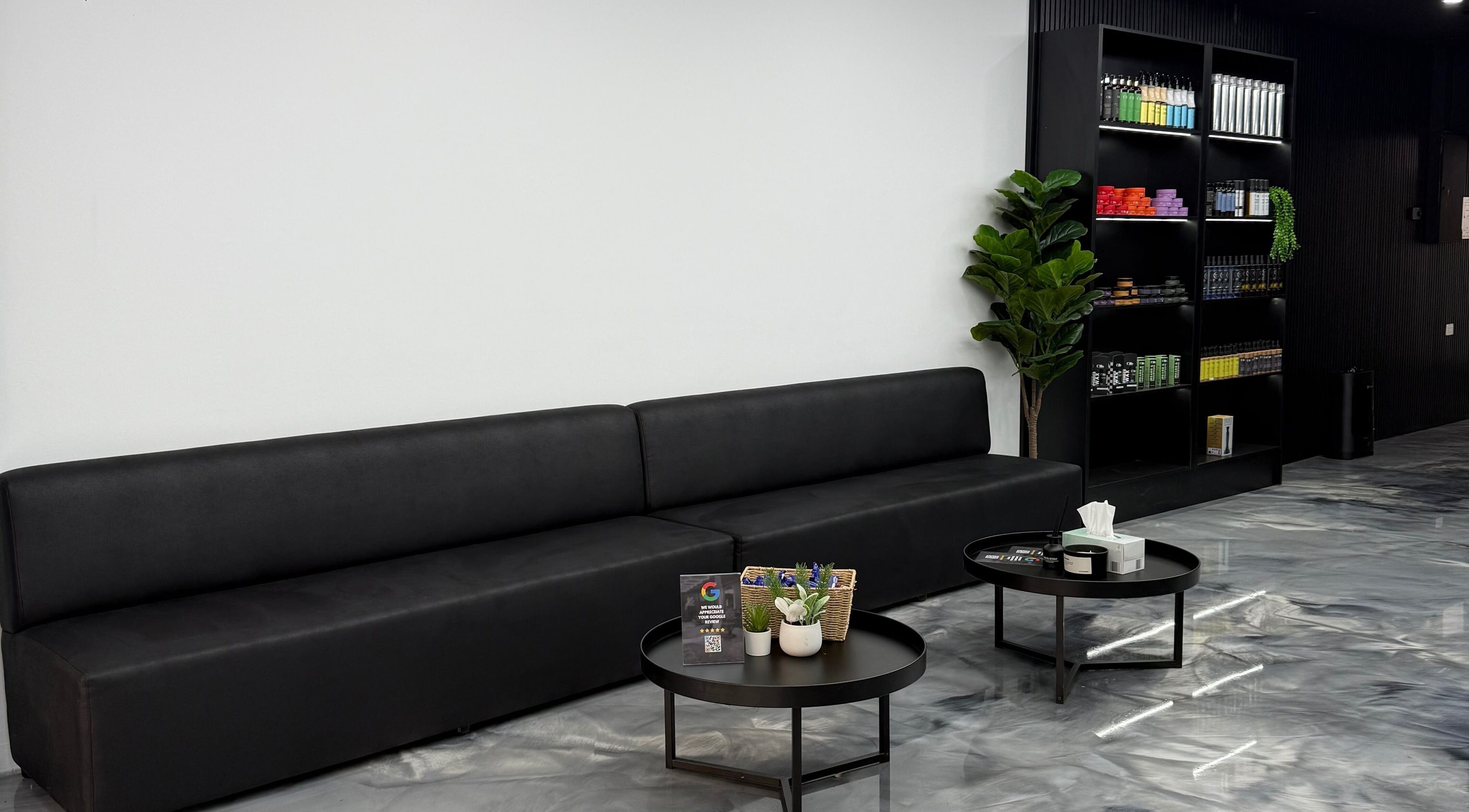 Stylish waiting area at JE Barbers, Melbourne, Victoria, AU with sleek black seating and modern decor.