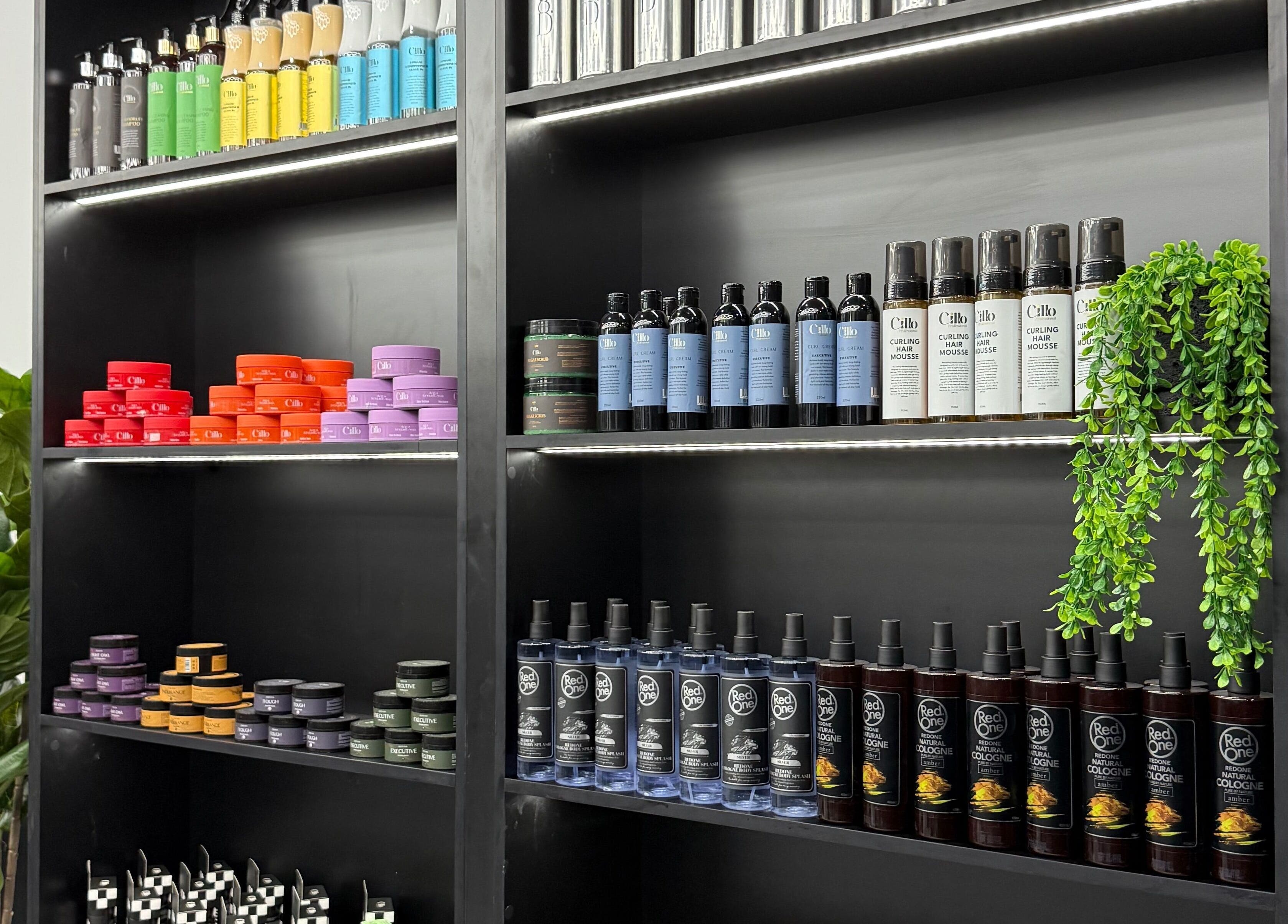 Diverse hair products on display at JE Barbers, Melbourne, Victoria, AU. Shelves neatly arranged with green plants.