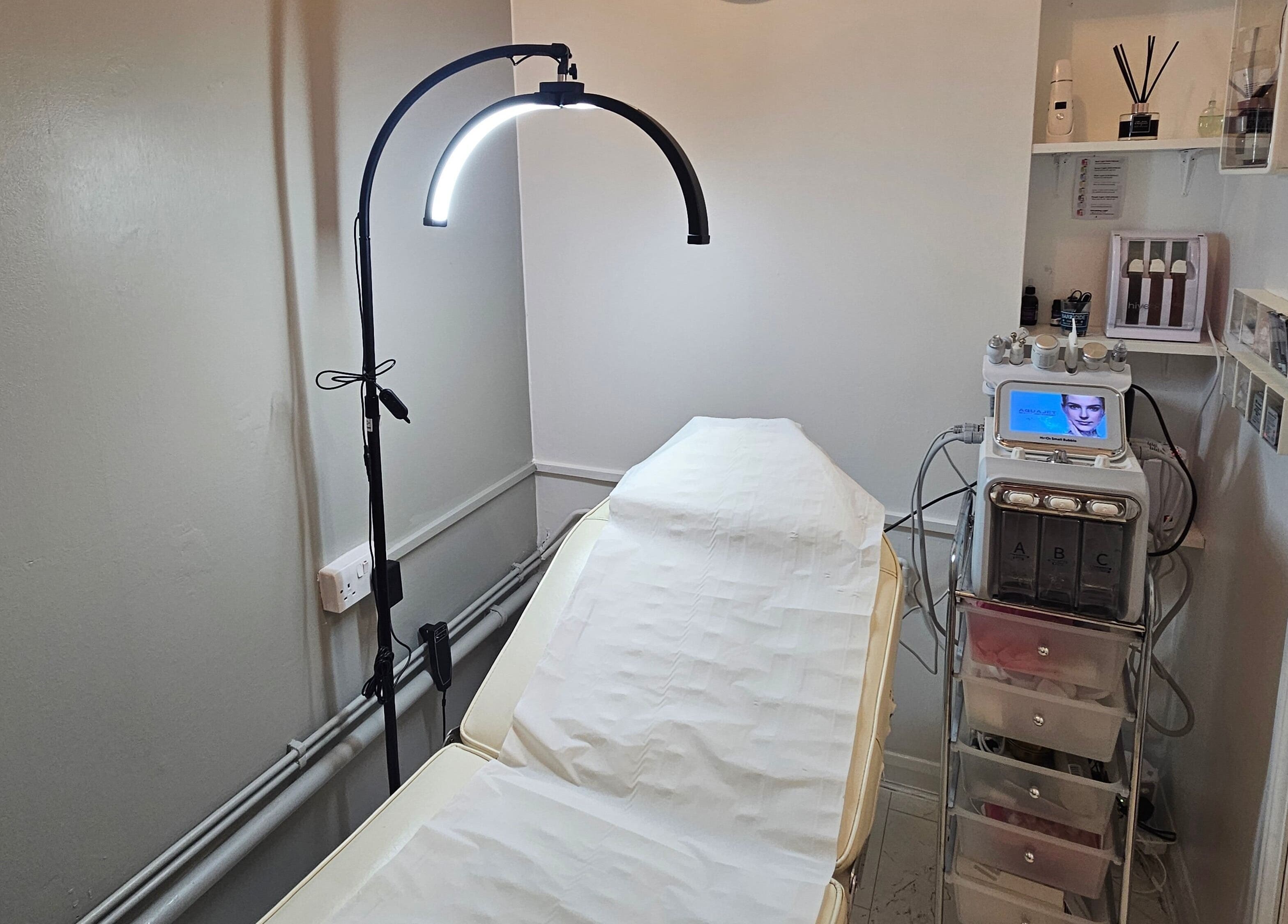 Treatment room at Pure Beauty Lounge in Hampton, England, GB, featuring a modern facial machine and therapy bed.