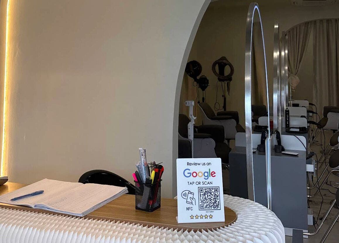 Reception desk at LILS SALON in Cyberjaya, featuring a Google review sign and comfortable styling chairs.