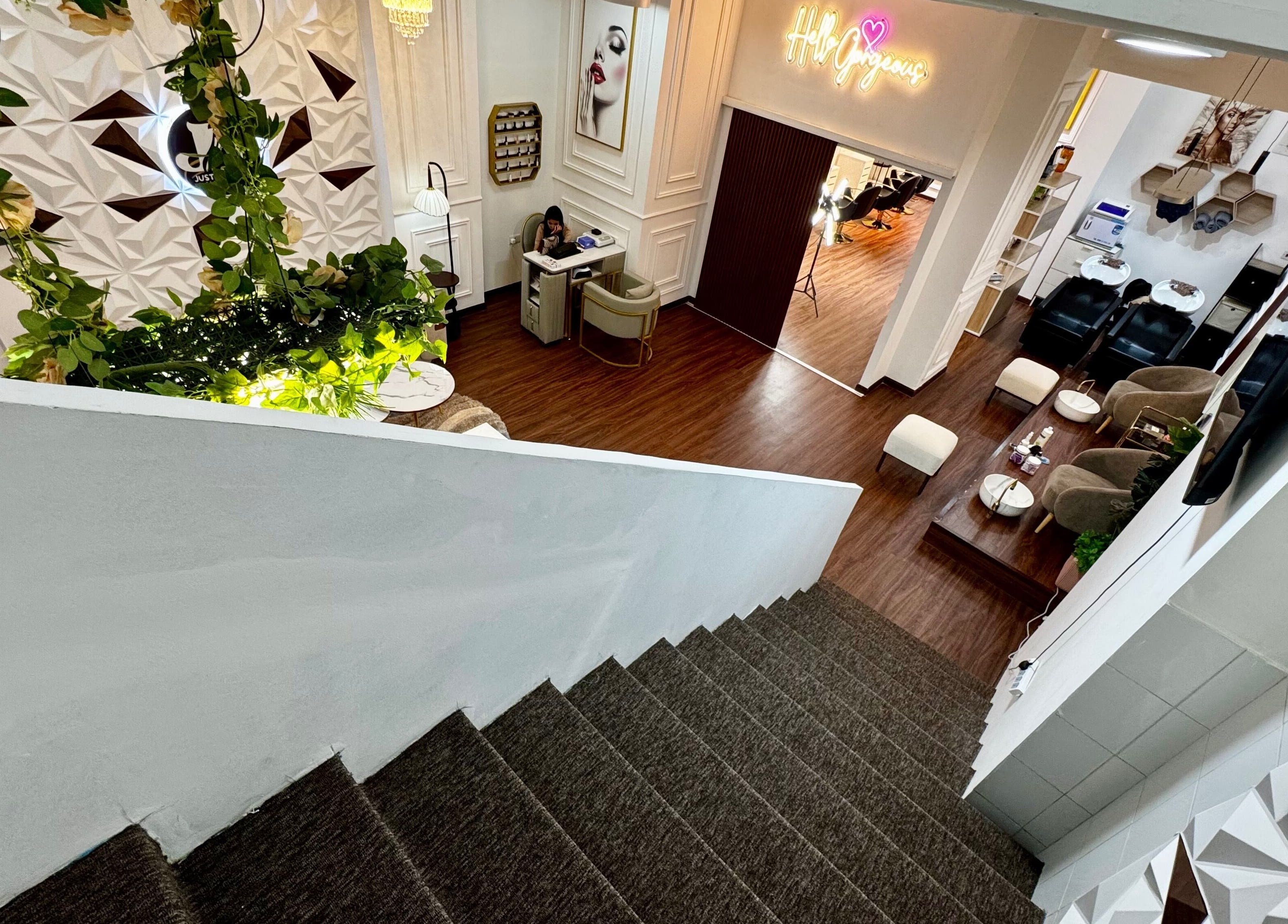 View from stairs of Just A Smile Beauty Salon(Ladies), Doha, showcasing a stylish interior with plants.