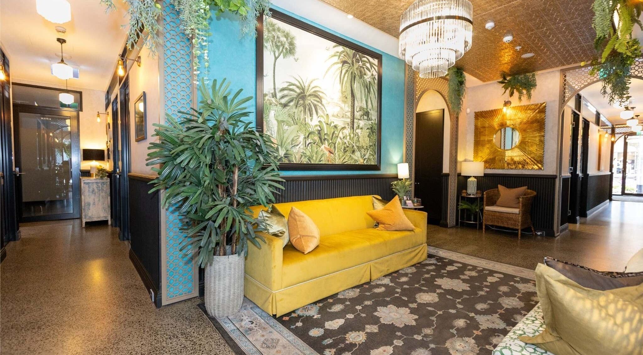 Chic lobby at Cry Baby Cosmetic Ink, Melbourne, Victoria, AU with tropical decor and yellow couch.