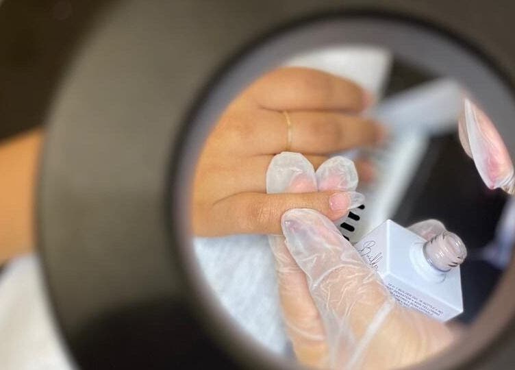 Close-up of a nail artist applying polish at betterfy, Riyadh, SA through a circular mirror.