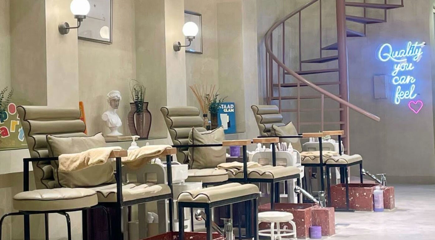 Luxurious pedicure chairs at Betterfy in Riyadh, SA, with a stylish spiral staircase and neon sign.