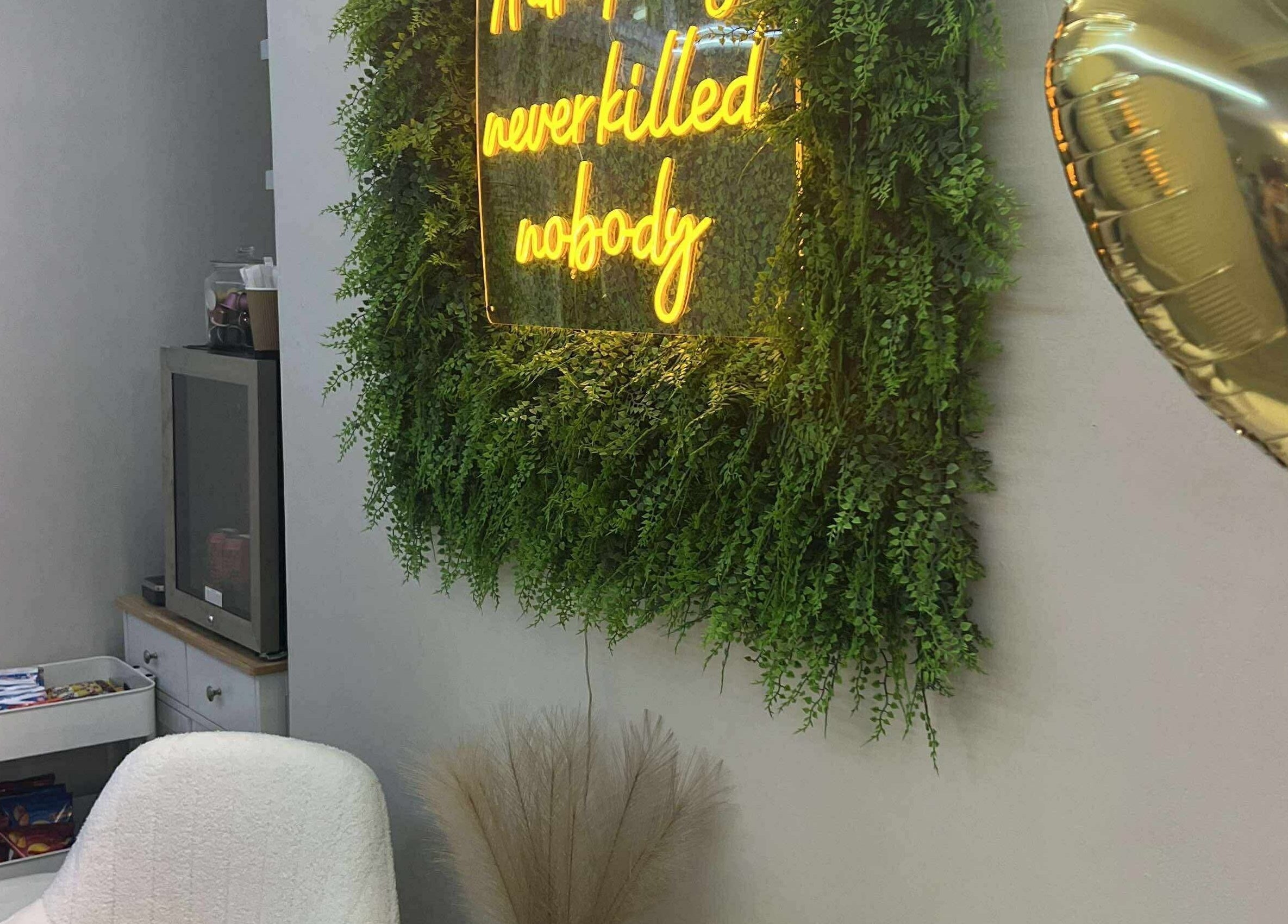 Cozy corner at Beauty by Courtney, Plymouth, England, GB with a neon sign and plush chair.