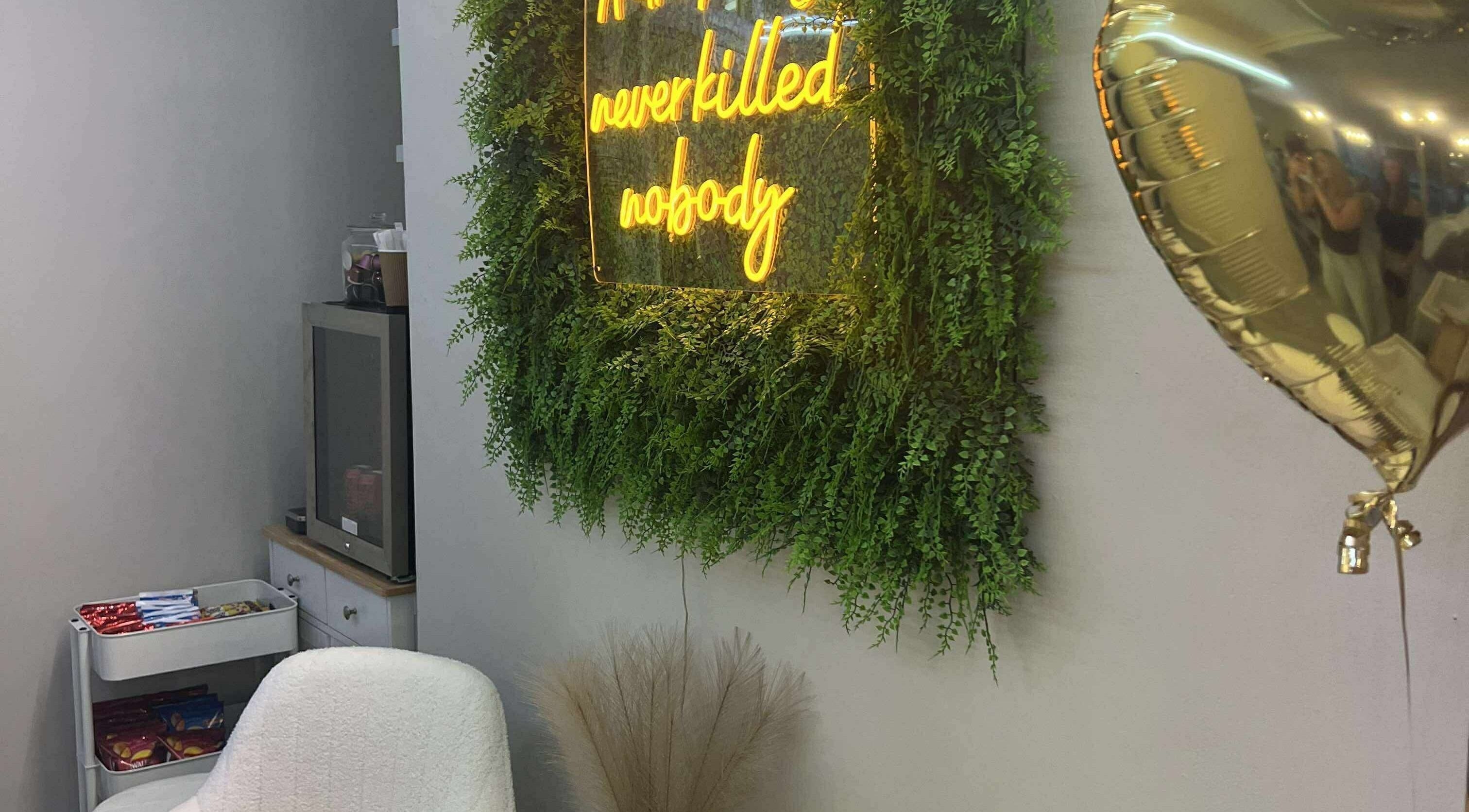 Cozy corner at Beauty by Courtney, Plymouth, England, GB with a neon sign and plush chair.