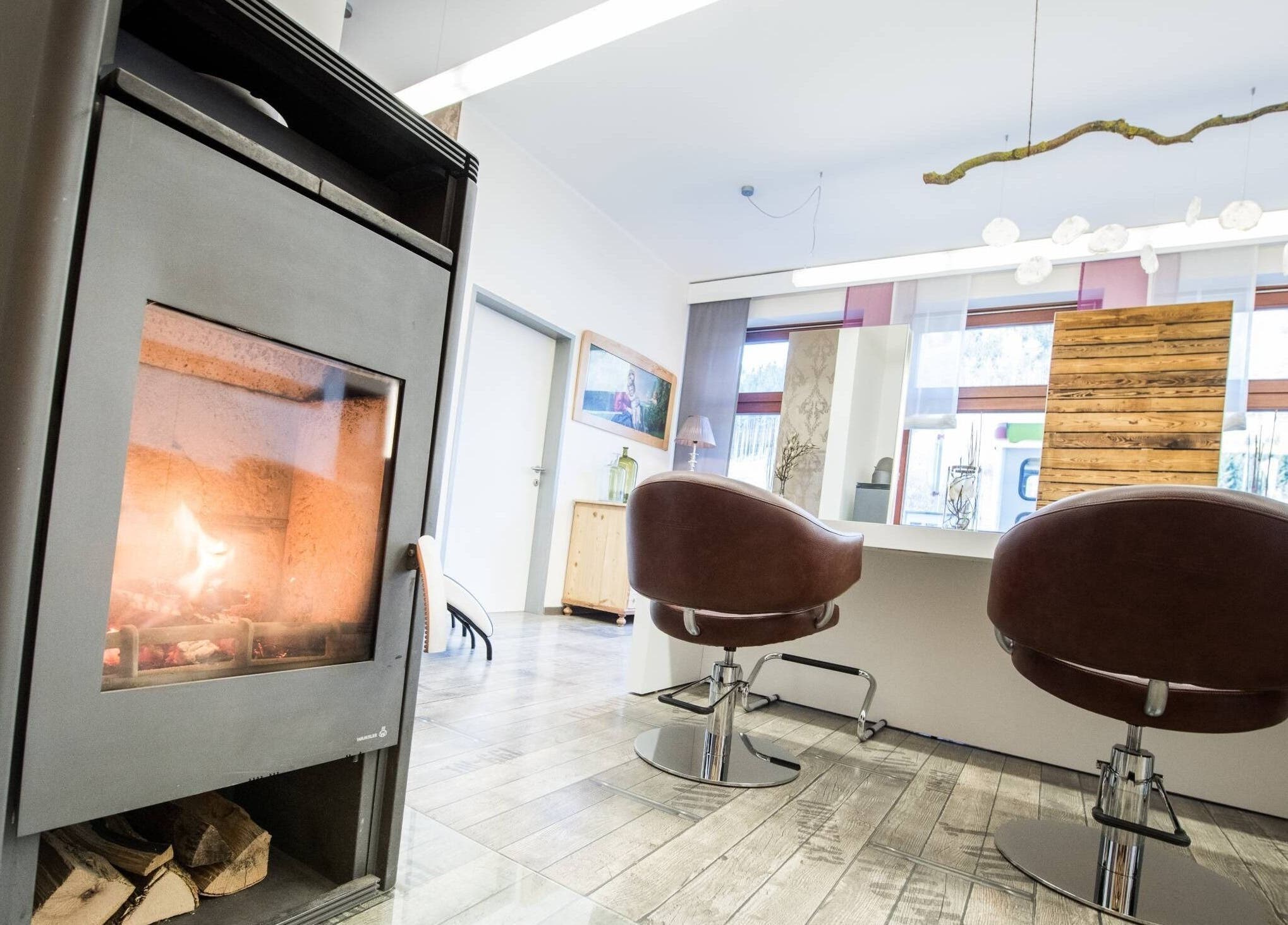 Warm salon at Aurion Labs in Wien, Wien, AT with stylish chairs and a cozy fireplace setting.