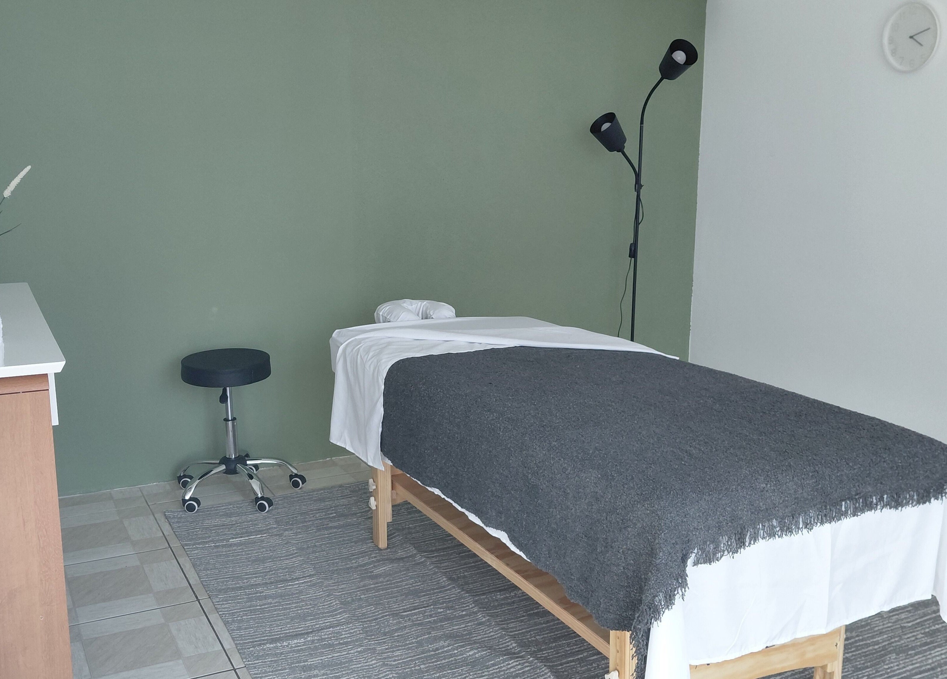 Sala de massagem acolhedora em Primícia Bem-Estar, Maringá, Paraná, BR, com cama terapêutica e decoração relaxante.