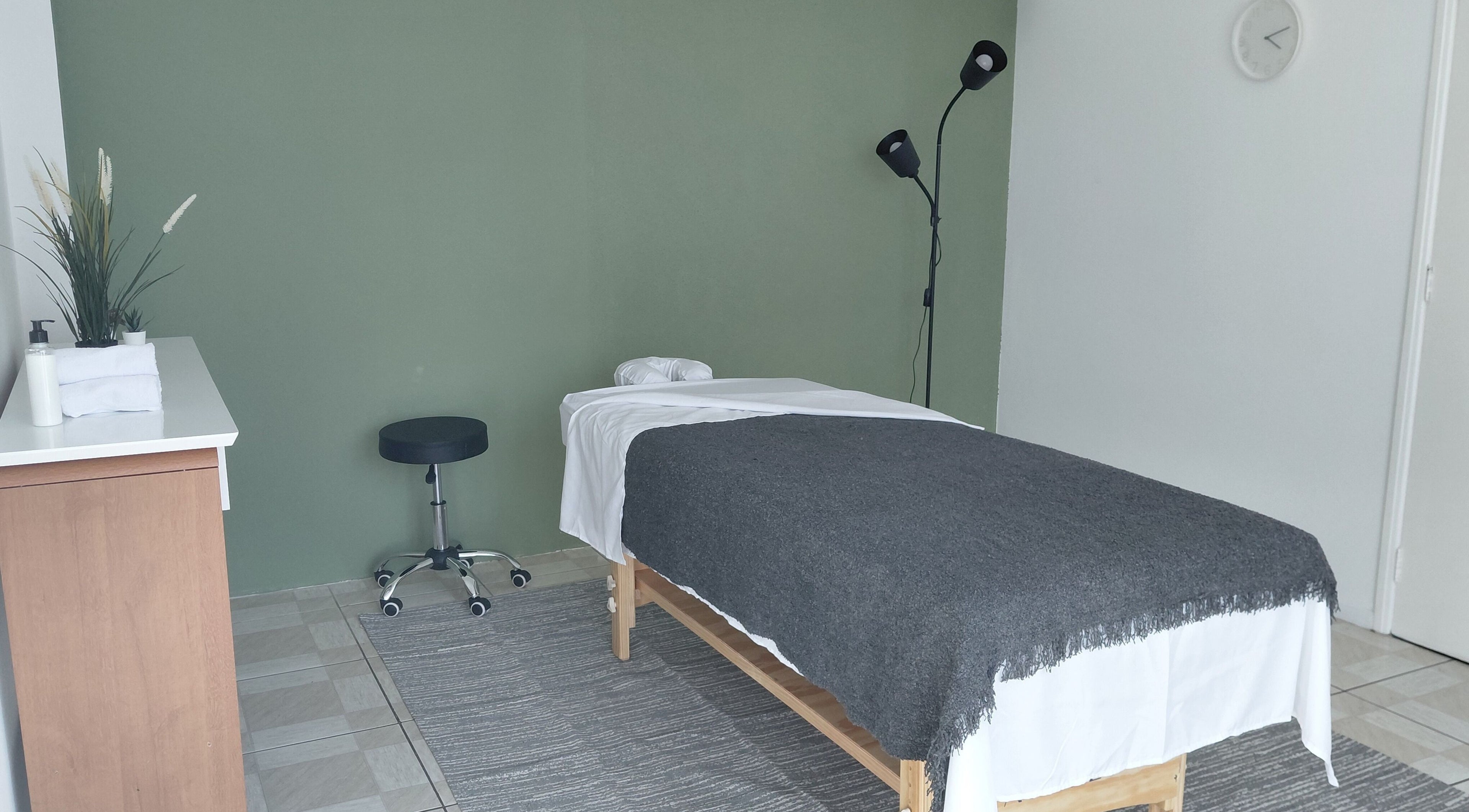 Sala de massagem acolhedora em Primícia Bem-Estar, Maringá, Paraná, BR, com cama terapêutica e decoração relaxante.