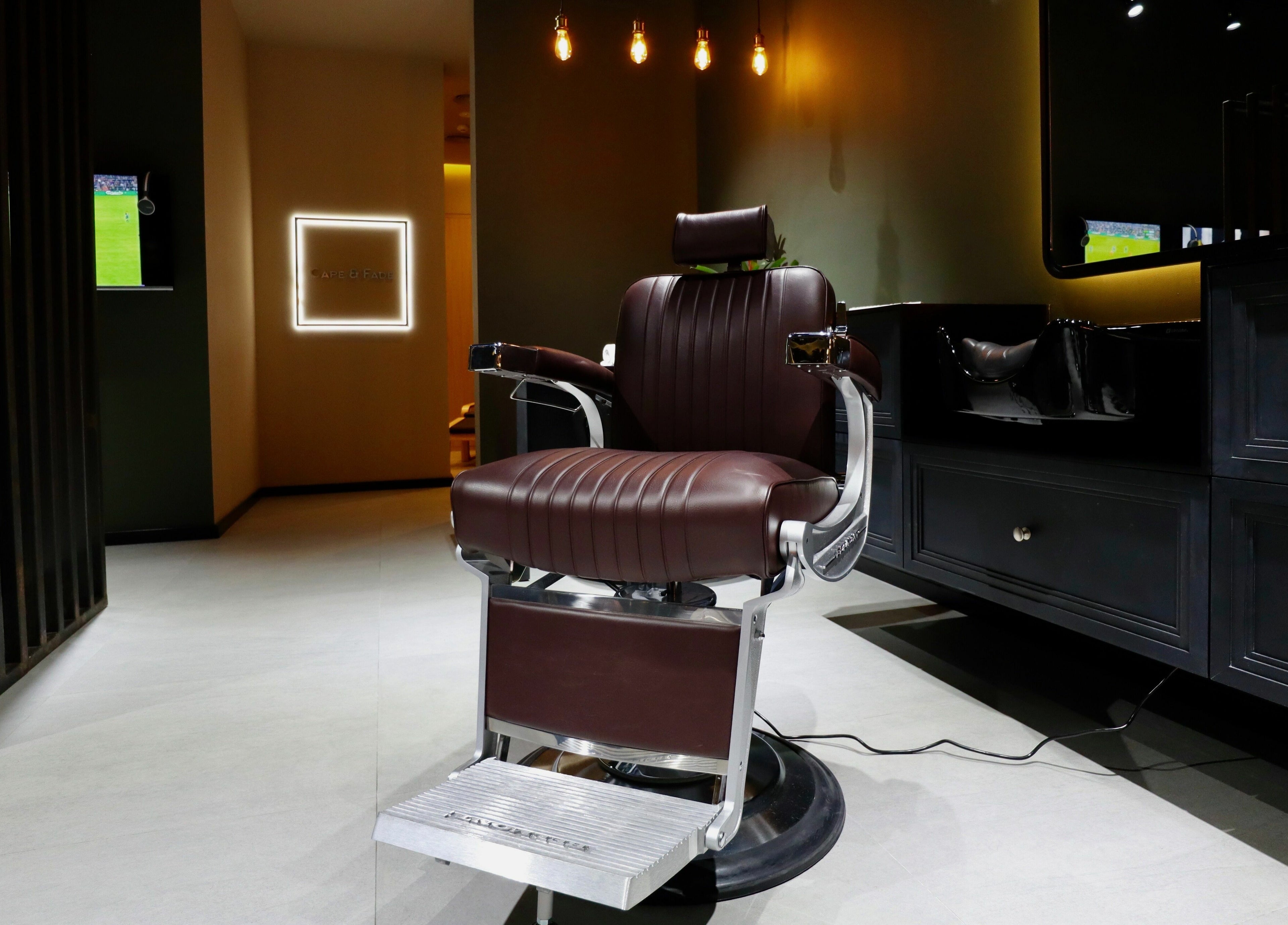 Luxurious barber chair at Cape & Fade, Dubai, AE, under warm lighting, showcasing modern design and comfort.