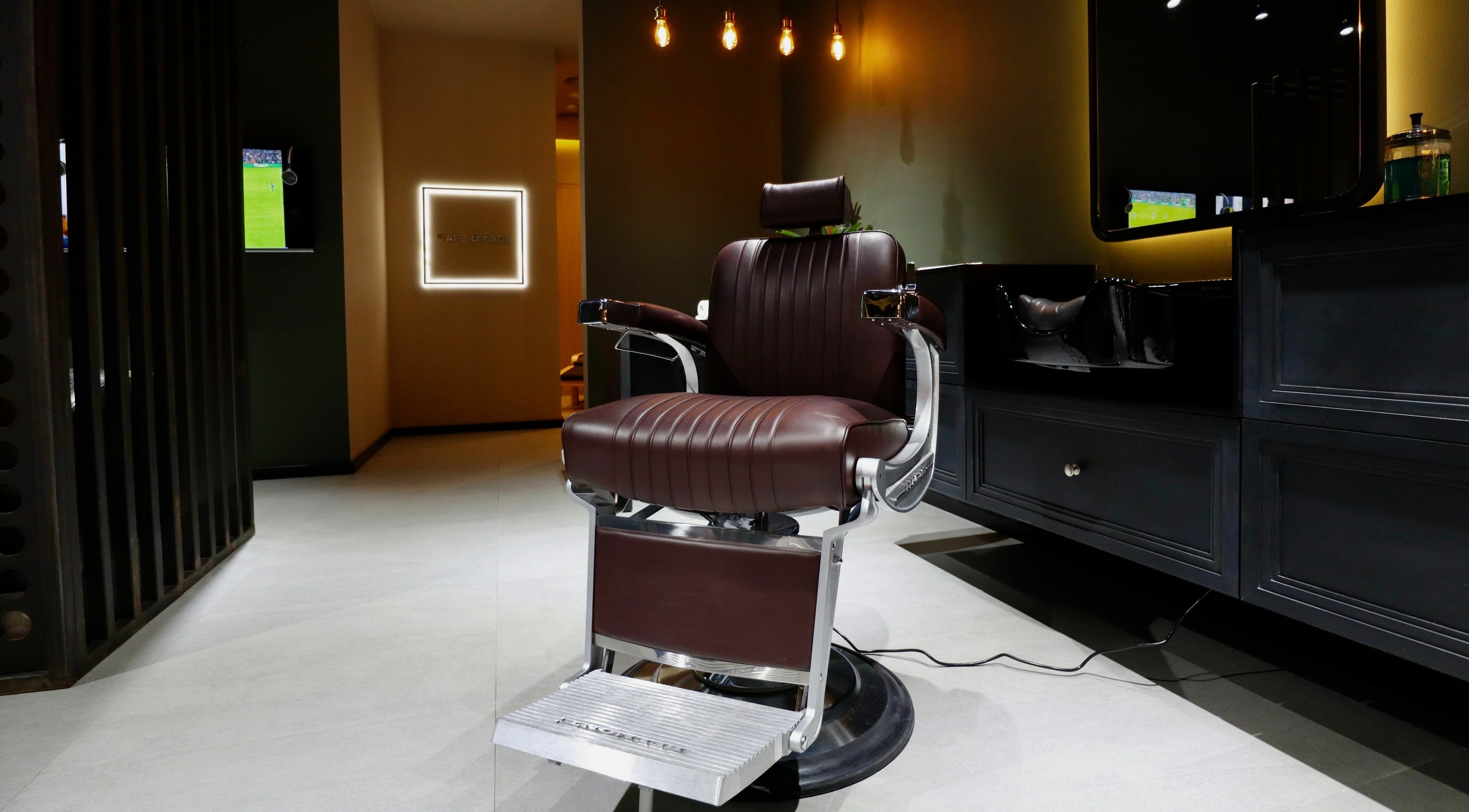 Luxurious barber chair at Cape & Fade, Dubai, AE, under warm lighting, showcasing modern design and comfort.