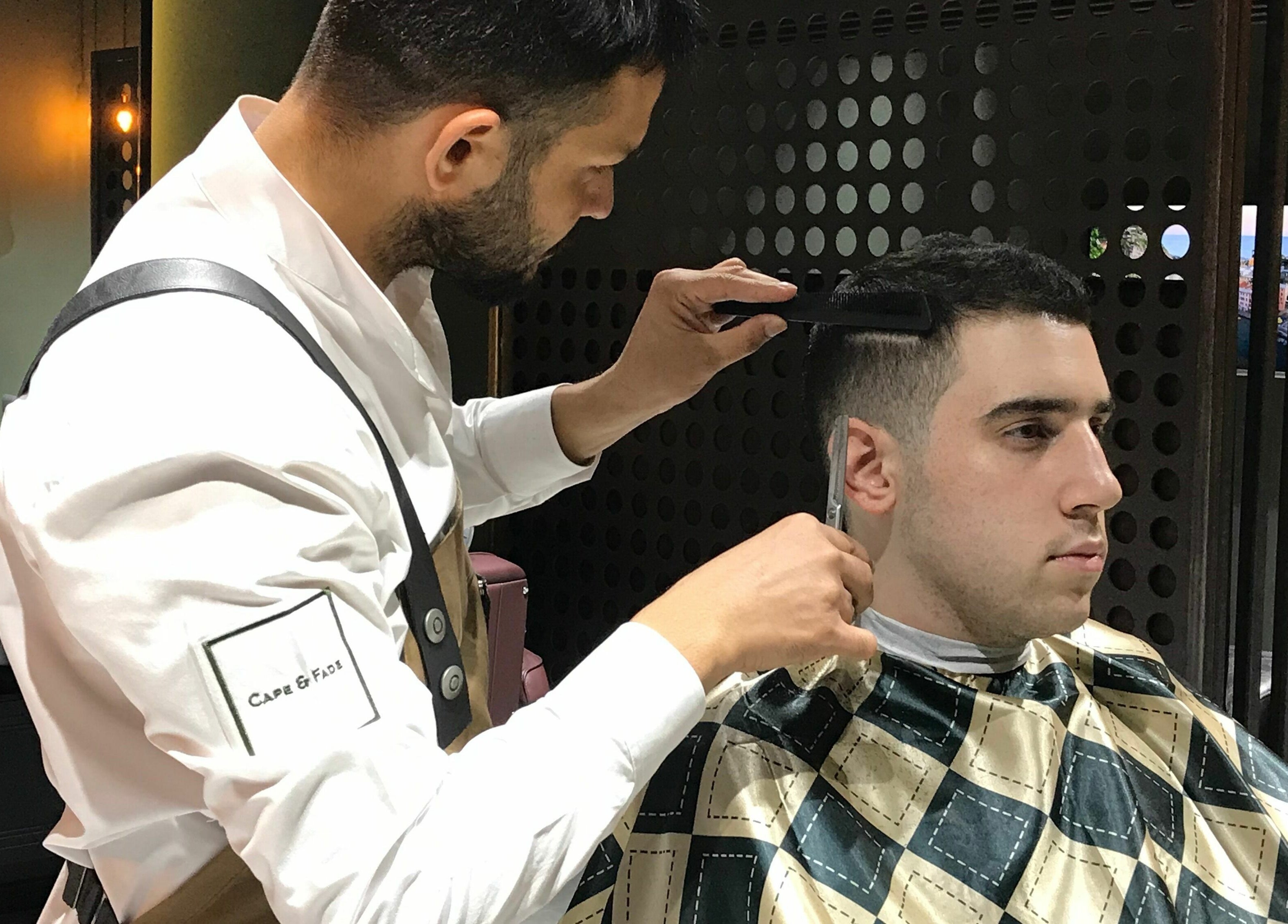Barber styling client's hair at Cape & Fade, Dubai, AE, showcasing precision and care.