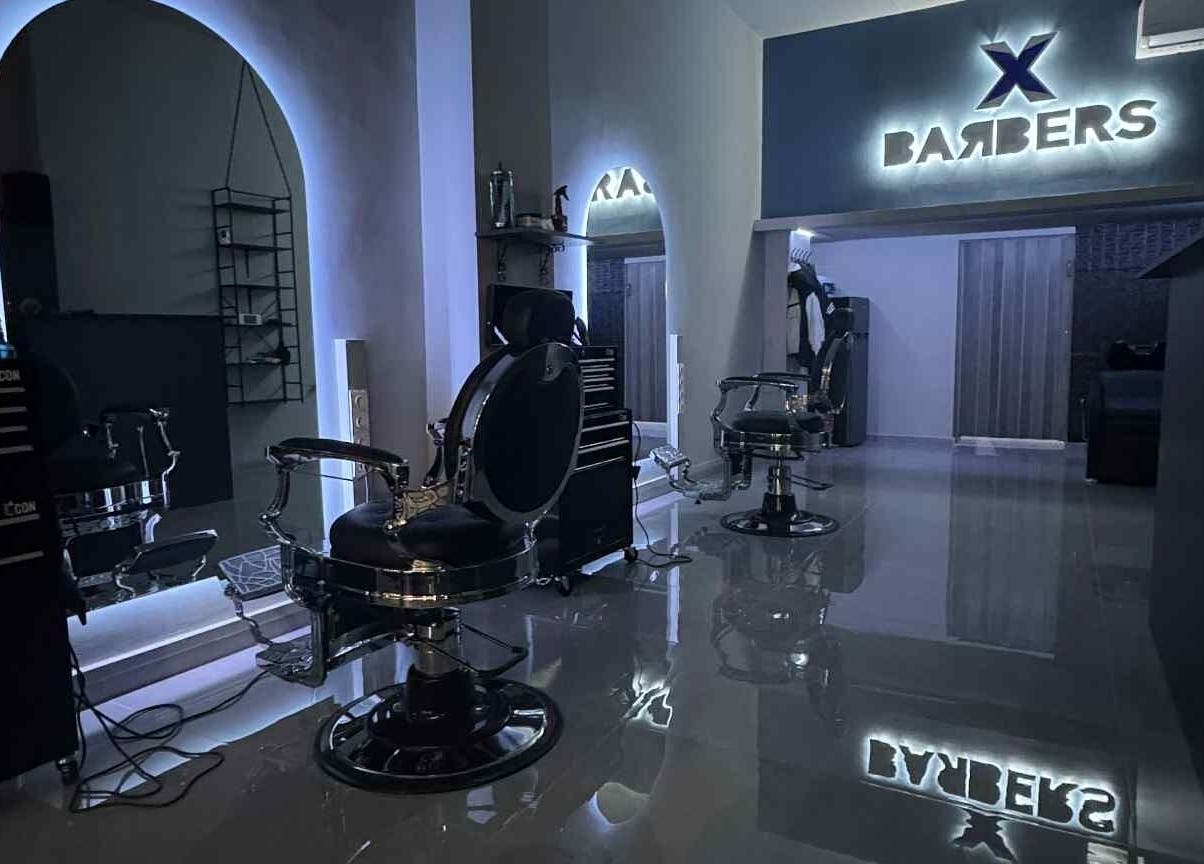 Εσωτερική άποψη της X BARBERS στη Λάρισα, GR με μοντέρνες καρέκλες και φωτισμό.