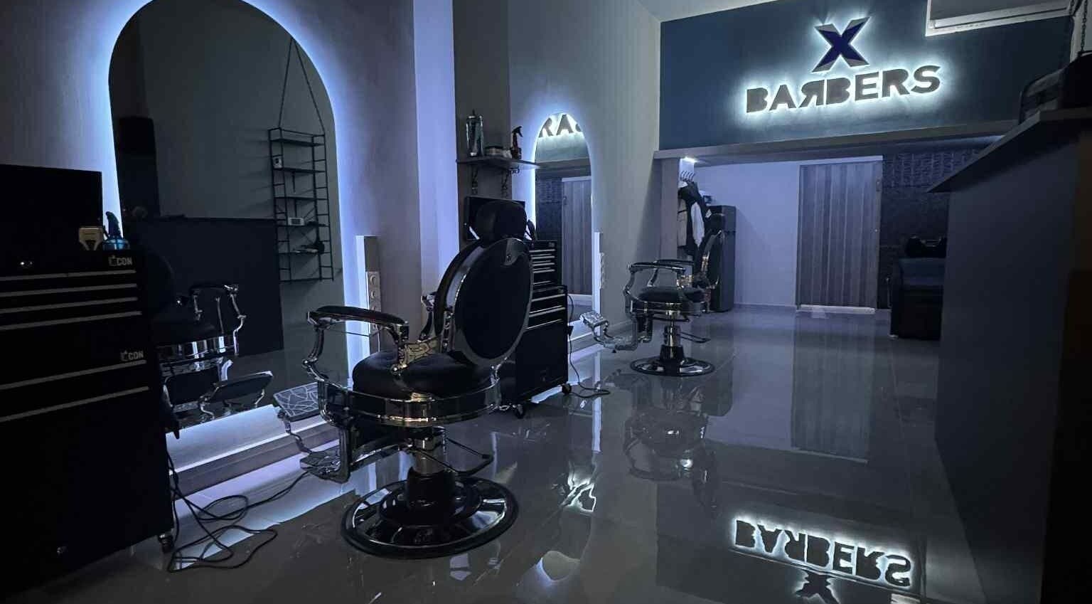 Εσωτερική άποψη της X BARBERS στη Λάρισα, GR με μοντέρνες καρέκλες και φωτισμό.
