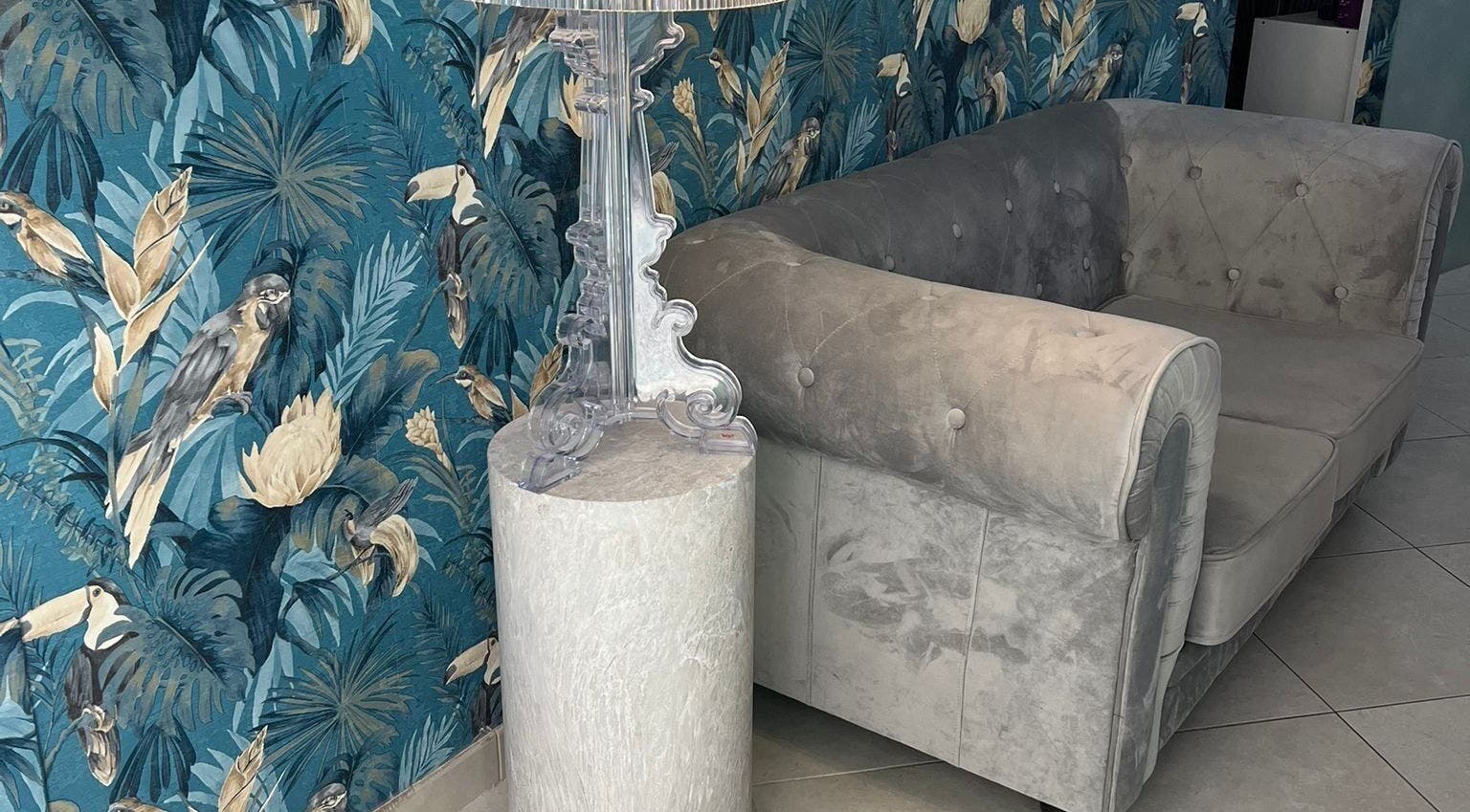 Interno accogliente di Adry Nails Centro a L'aquila, Abruzzo, IT con divano elegante e carta da parati tropicale.