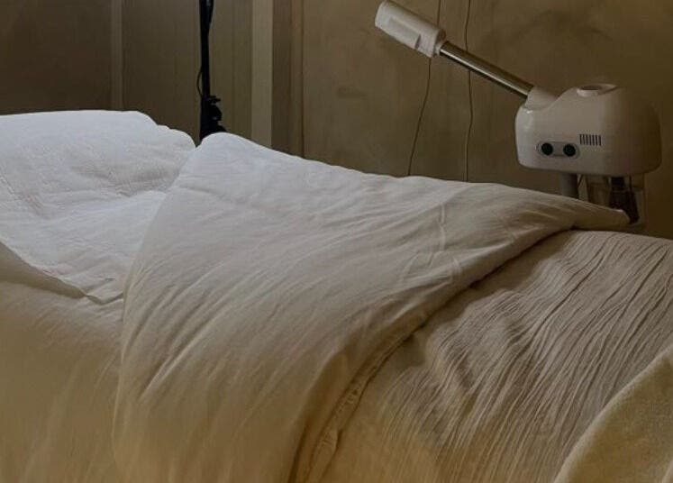 Cozy treatment bed at Surya Skin + Wellness, Reigate, England, GB, creates a serene, welcoming atmosphere for clients.