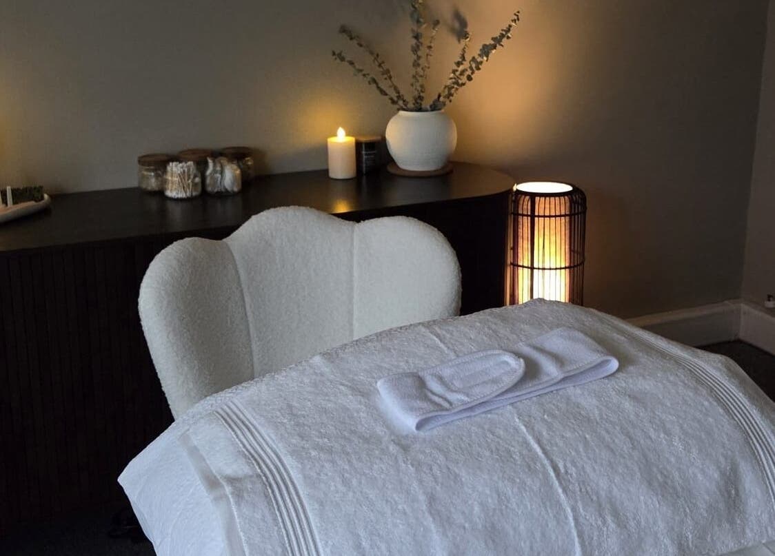 Serene treatment room at Surya Skin + Wellness, Reigate, England, GB, featuring a cozy chair and candle-lit ambiance.