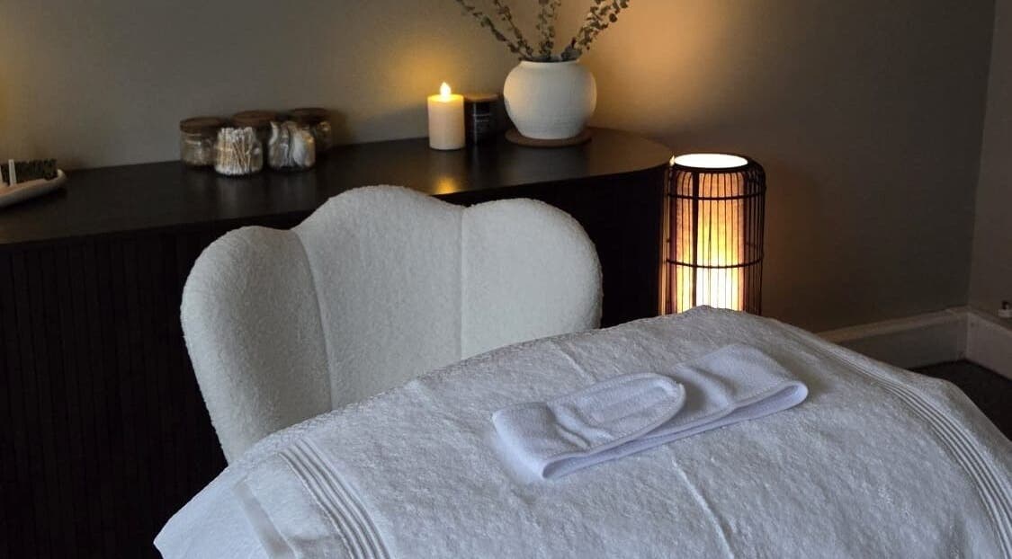 Serene treatment room at Surya Skin + Wellness, Reigate, England, GB, featuring a cozy chair and candle-lit ambiance.