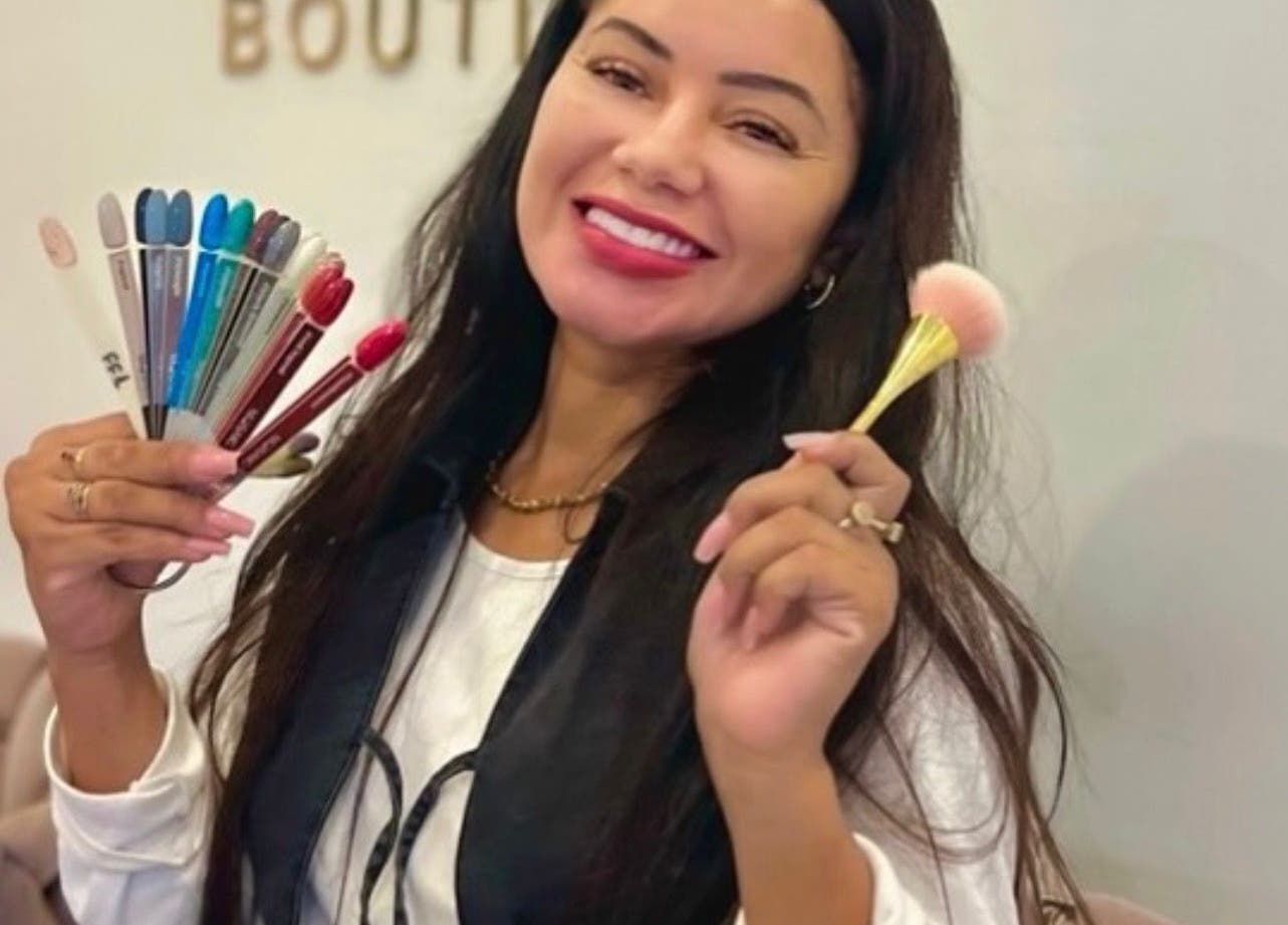 Smiling woman showcases nail colors and brush at Bluma Nail Bar, Tas-sliema, MT.