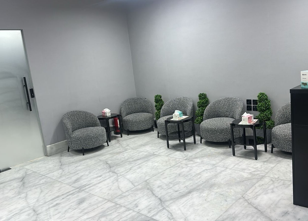 Comfortable waiting area at AJ Barbershop, Jeddah, Makkah Province, SA with gray seating and sleek decor.
