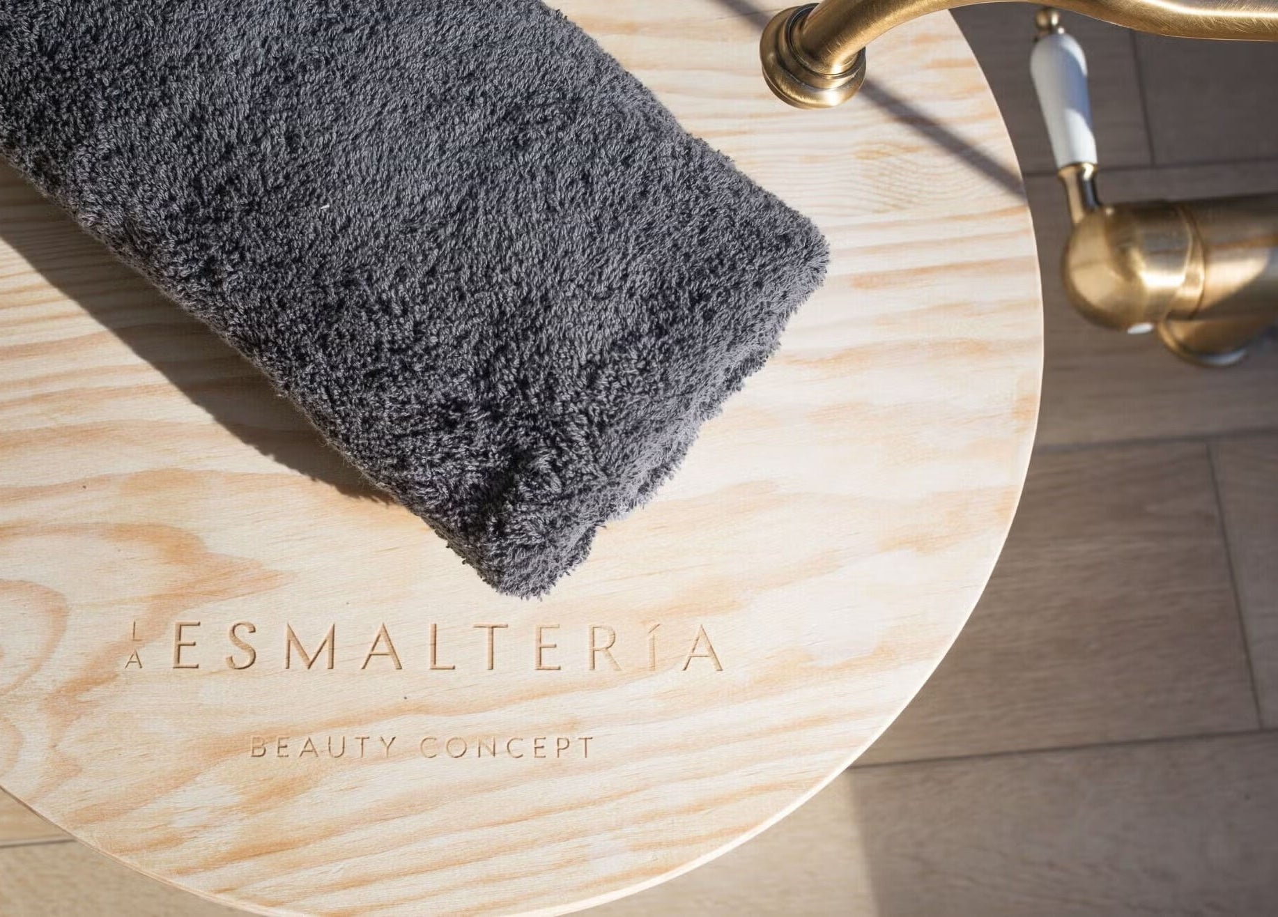 Toalla gris sobre mesa de madera en La Esmalteria Aravaca, Madrid, Comunidad De Madrid, ES.