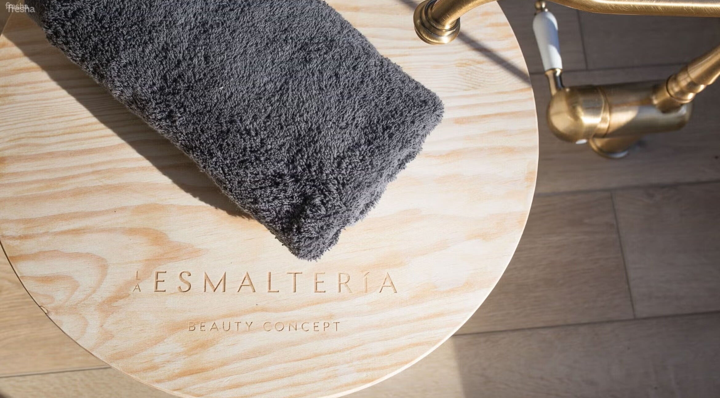 Toalla gris sobre mesa de madera en La Esmalteria Aravaca, Madrid, Comunidad De Madrid, ES.