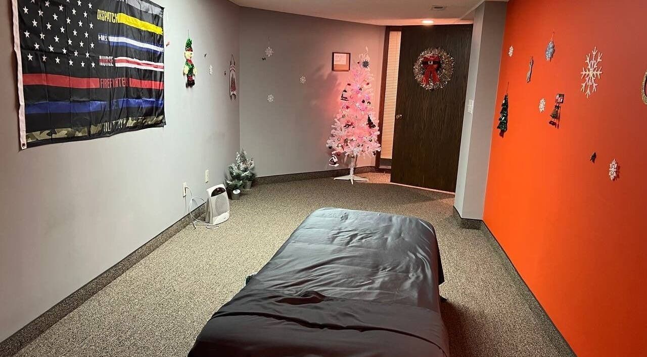 Restore Therapy LLC在明尼苏达州阿诺卡市的舒适疗养室，配有装饰挂饰和治疗床。