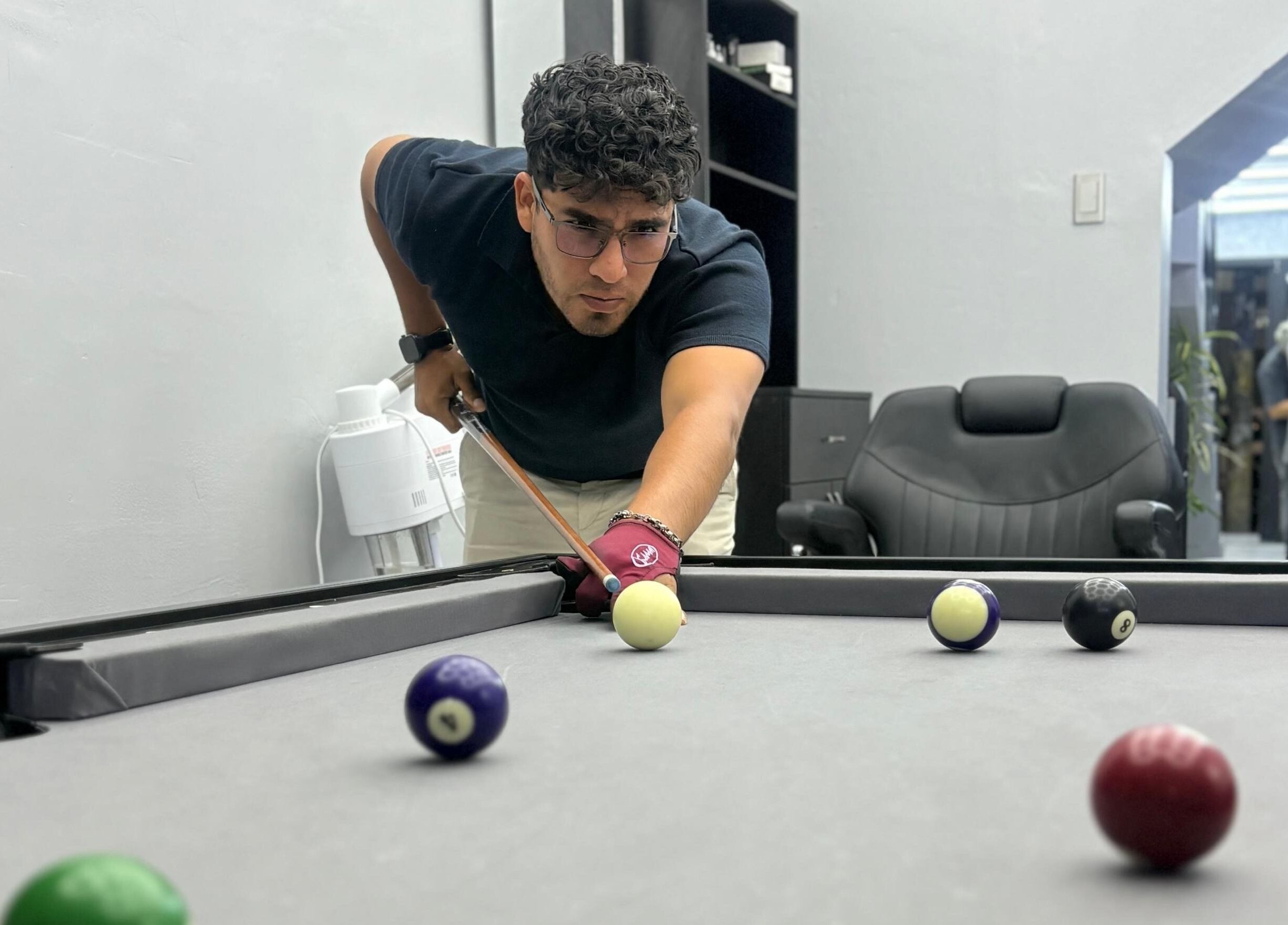 Cliente juega billar en VIKINGARD BARBER STUDIO, Chiclayo, Lambayeque, PE. Ambiente elegante y relajado.
