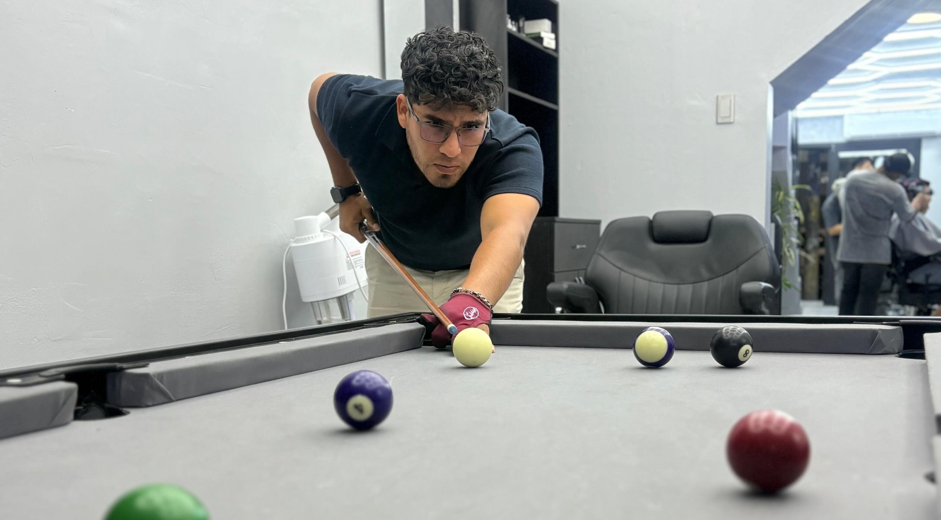 Cliente juega billar en VIKINGARD BARBER STUDIO, Chiclayo, Lambayeque, PE. Ambiente elegante y relajado.