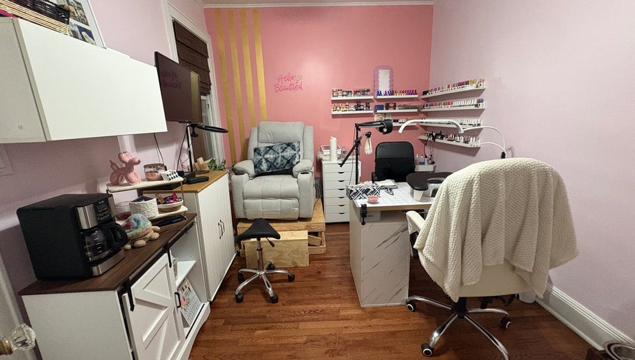 Cozy nail studio at Nailsbyflor in New York, featuring plush seating and a vibrant pink wall with polish displays.