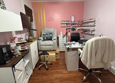 Cozy nail studio at Nailsbyflor in New York, featuring plush seating and a vibrant pink wall with polish displays.
