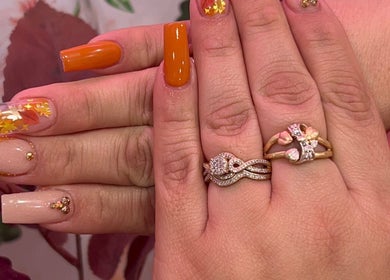 Autumn-themed nail art at Nailsbyflor, New York, New York, US. Features orange and gold design with leaf accents.
