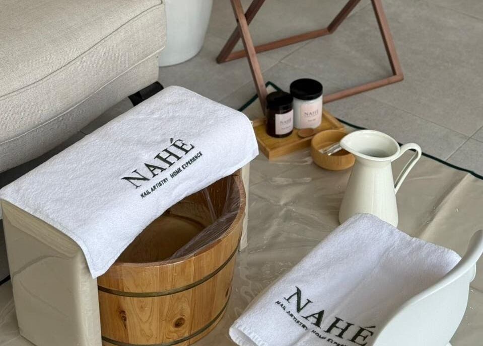 Relaxing foot bath setup at Nahé Beauty Home Service Salon in Dubai, AE with towels and spa products.