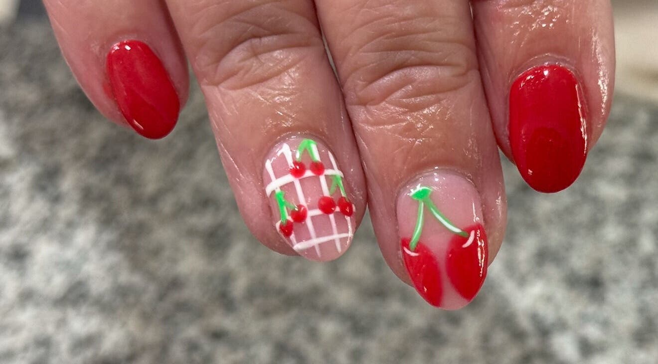 Cherry-themed nail art at Glimmer Nail Studio, Oshkosh, Wisconsin, US. Red and patterned designs showcased beautifully.