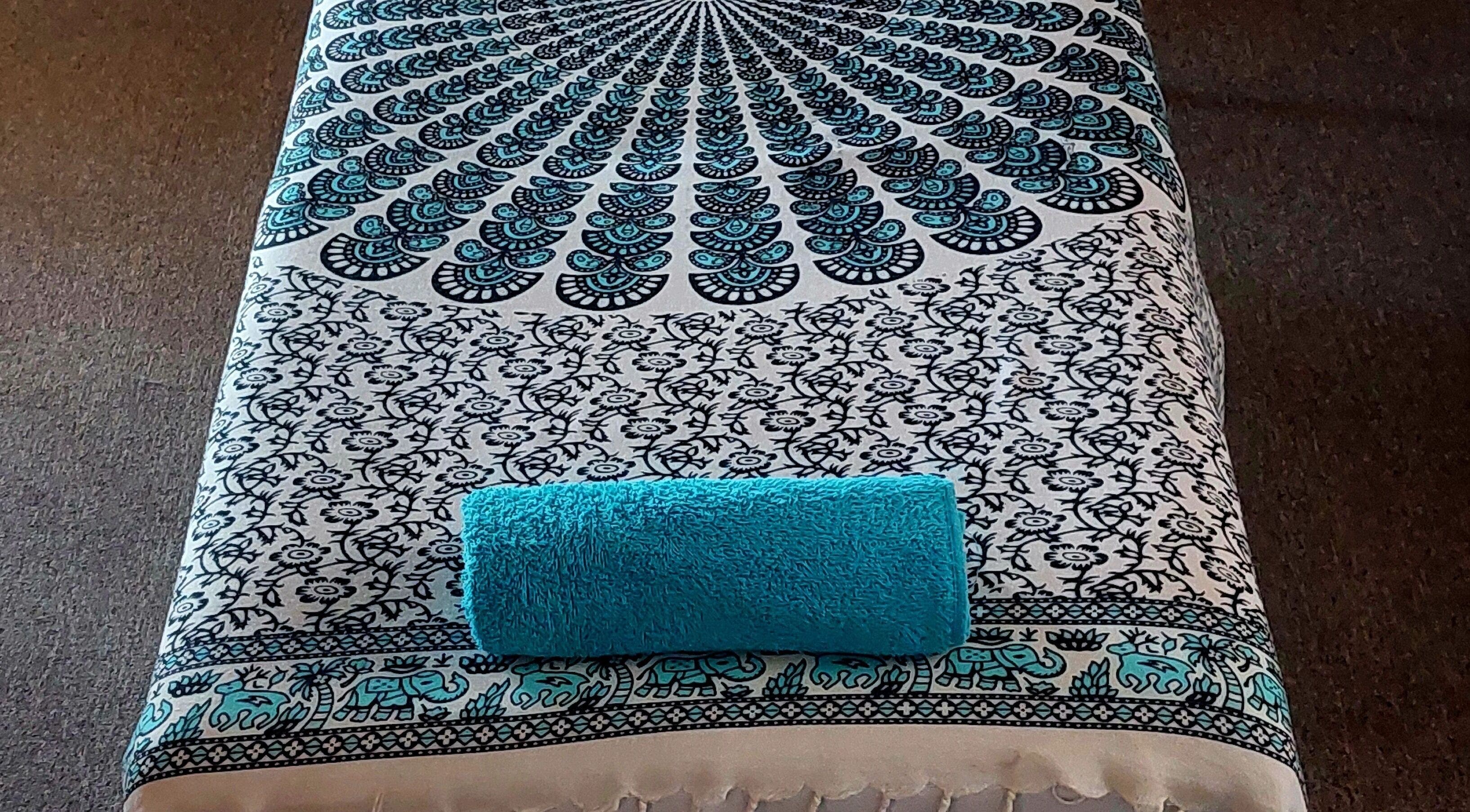 Massage table with a patterned cover and blue towel at LomiLomi Therapeutic Massage, Jeffreys Bay, Eastern Cape, ZA.