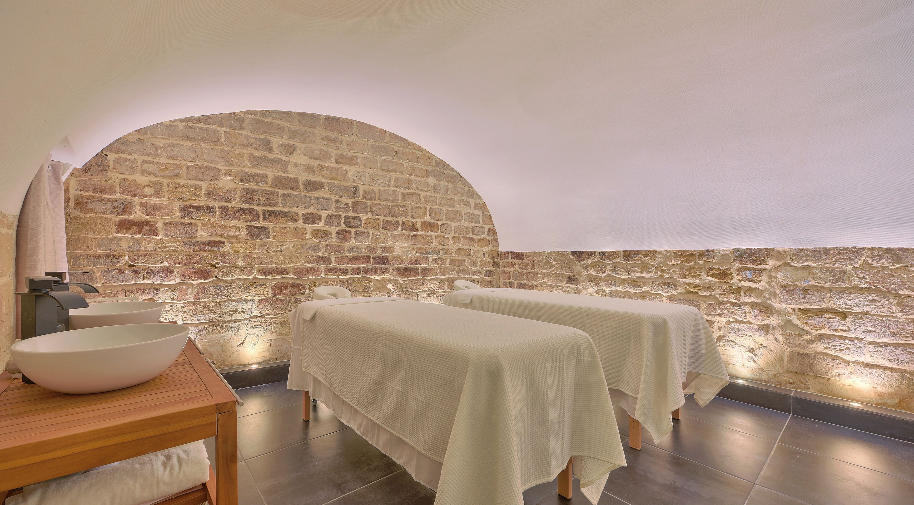 Salle de massage sereine à l'Institut Berry - Paris 4, Paris, Île-de-France, FR avec lits et murs en pierre.