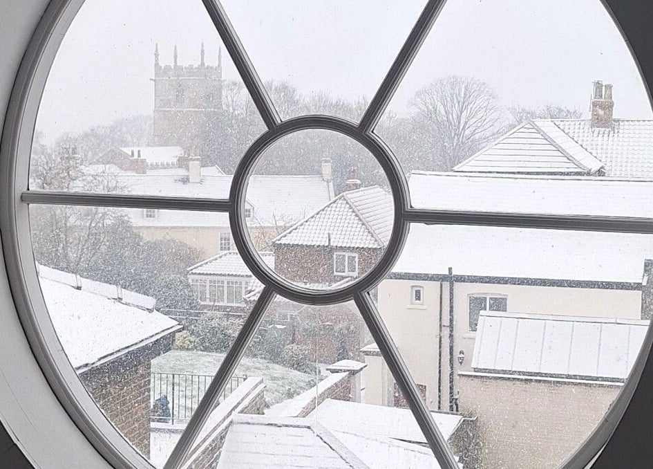Snowy view through round window at Chelsea Louise, Caistor, England, GB showcasing beauty and tranquility.