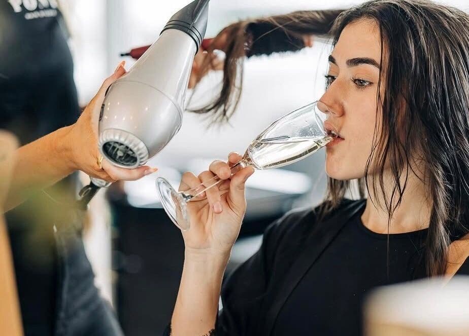 Client enjoying drink during hair blowout at PONY HAIR SOCIETY, The Junction, New South Wales, AU.