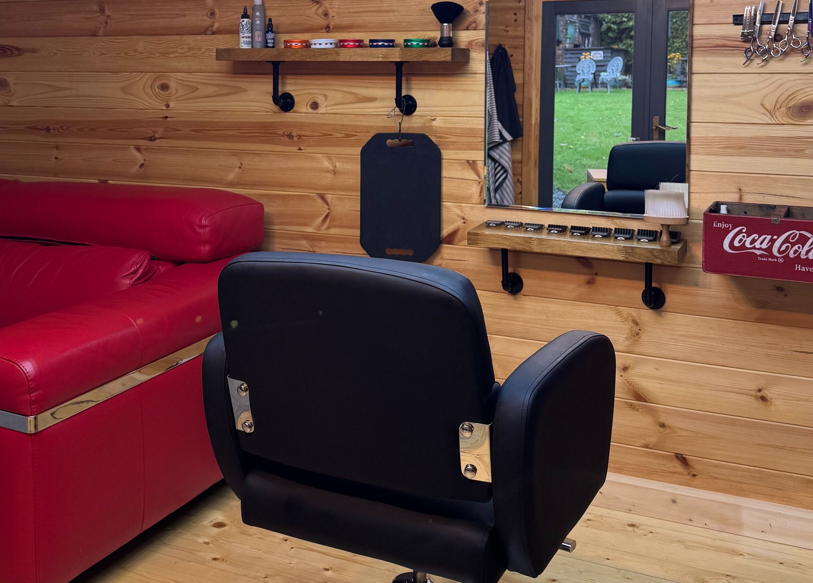 Interior of Barbering by Teegs in Hawkhurst, England showcasing a stylish chair and red couch.