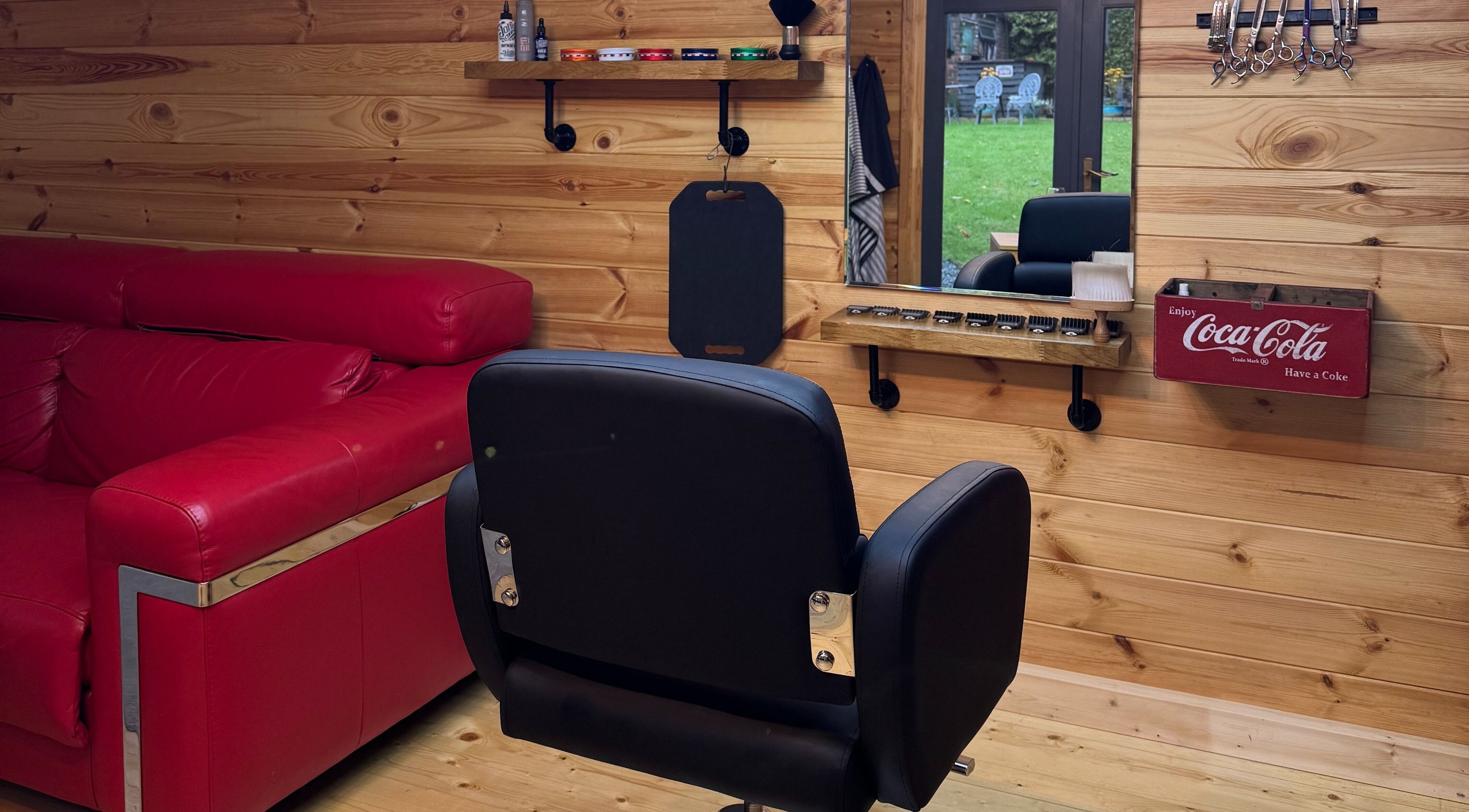 Interior of Barbering by Teegs in Hawkhurst, England showcasing a stylish chair and red couch.