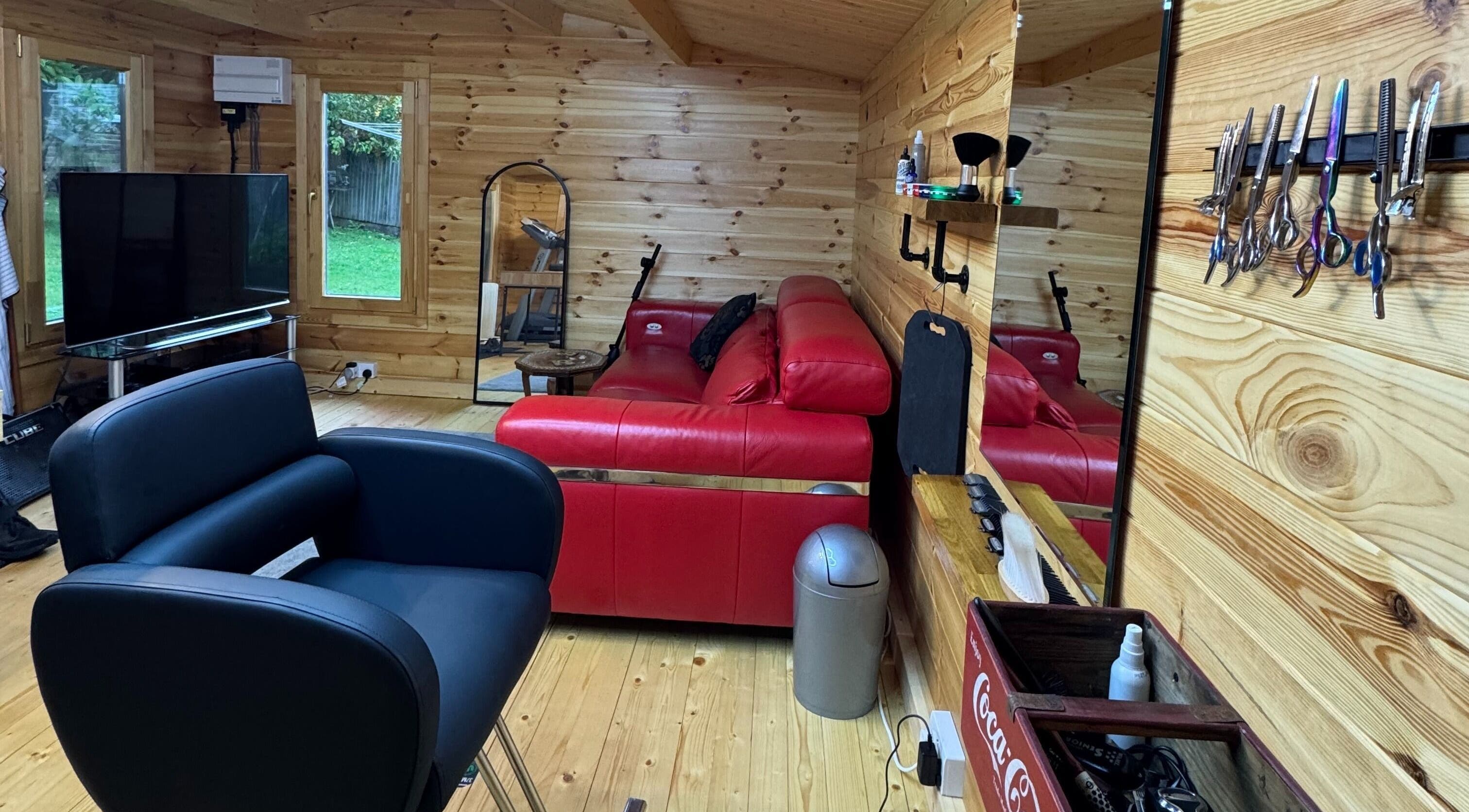 Inviting barber space at Barbering by Teegs in Hawkhurst, England, GB with modern chair and red sofa.