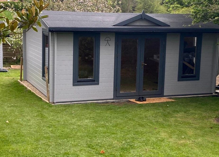 Exterior of Barbering by Teegs' tranquil garden studio in Hawkhurst, England, GB, surrounded by greenery.