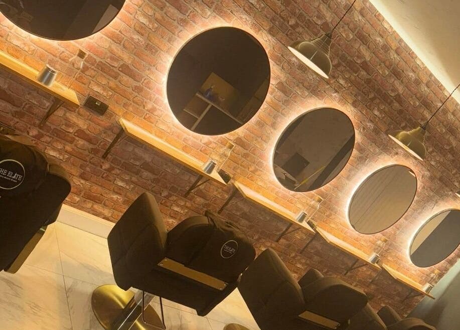 Modern salon interior at Sophie Hair Artist in Thetford, England, GB with illuminated mirrors and styling chairs.