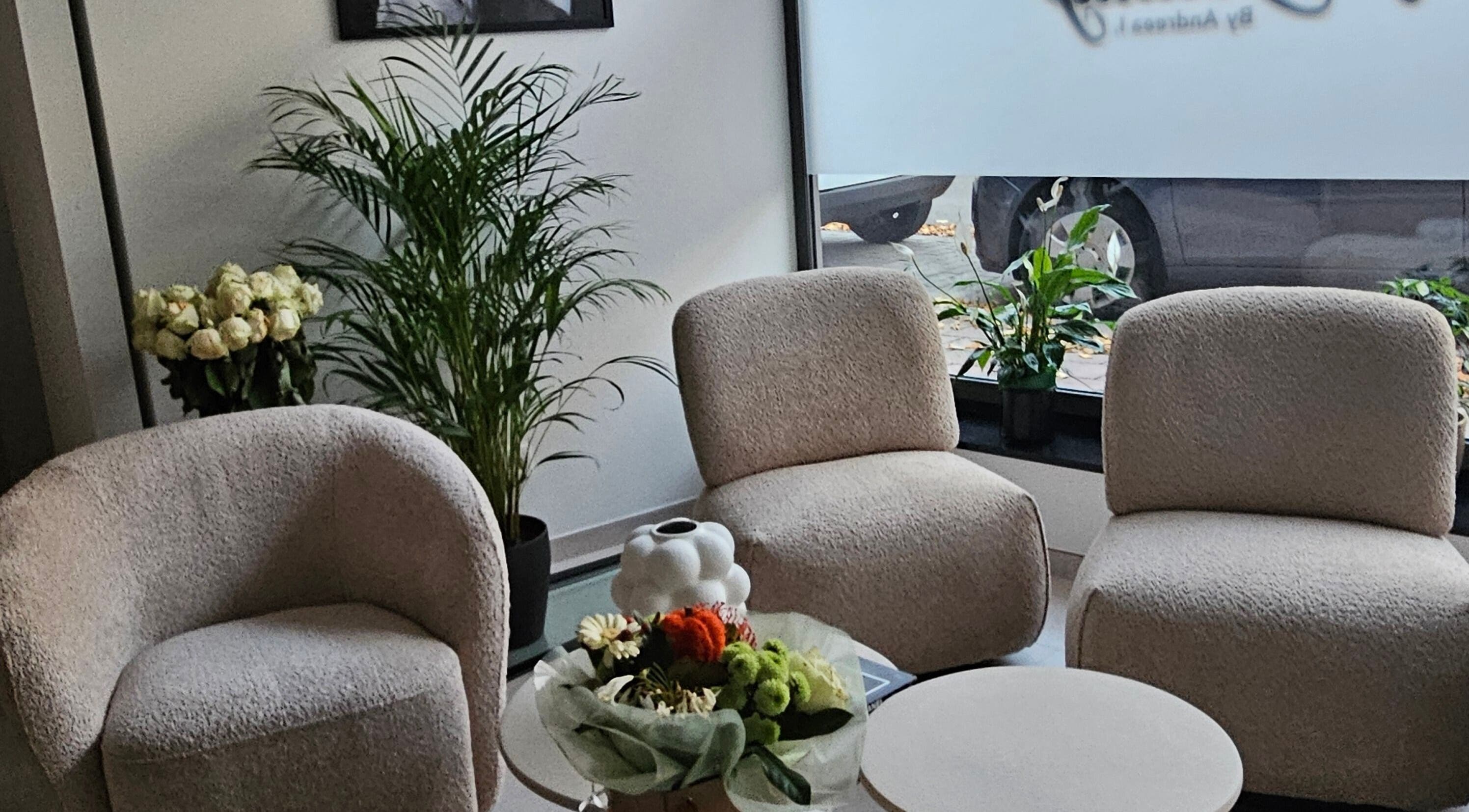 Zona de relaxare elegantă la Loly' lasers, Zellik, Bruxelles, BE, cu scaune albe și plante verzi.