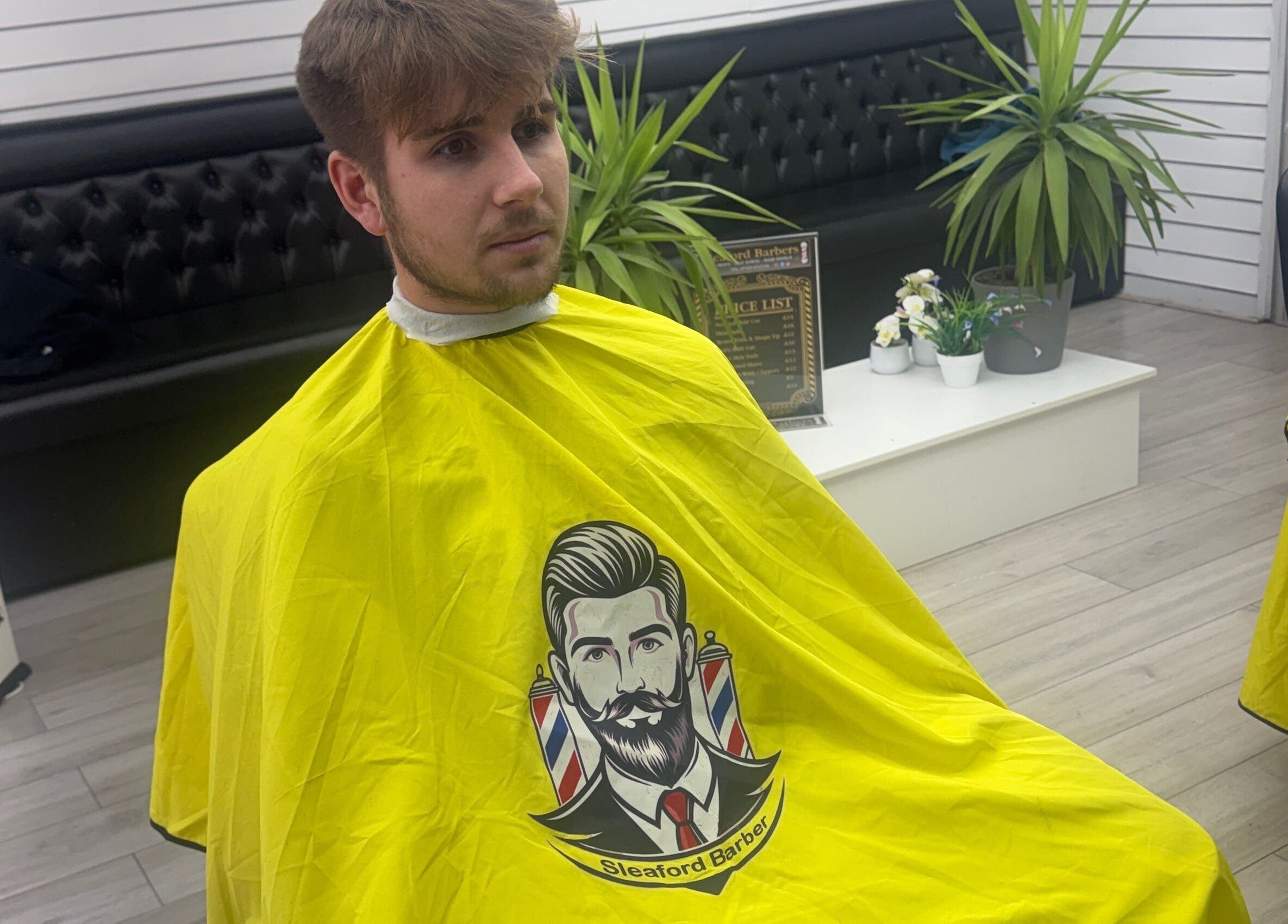 Client at Sleaford Barbers in London, England, wearing a cape during haircut session.