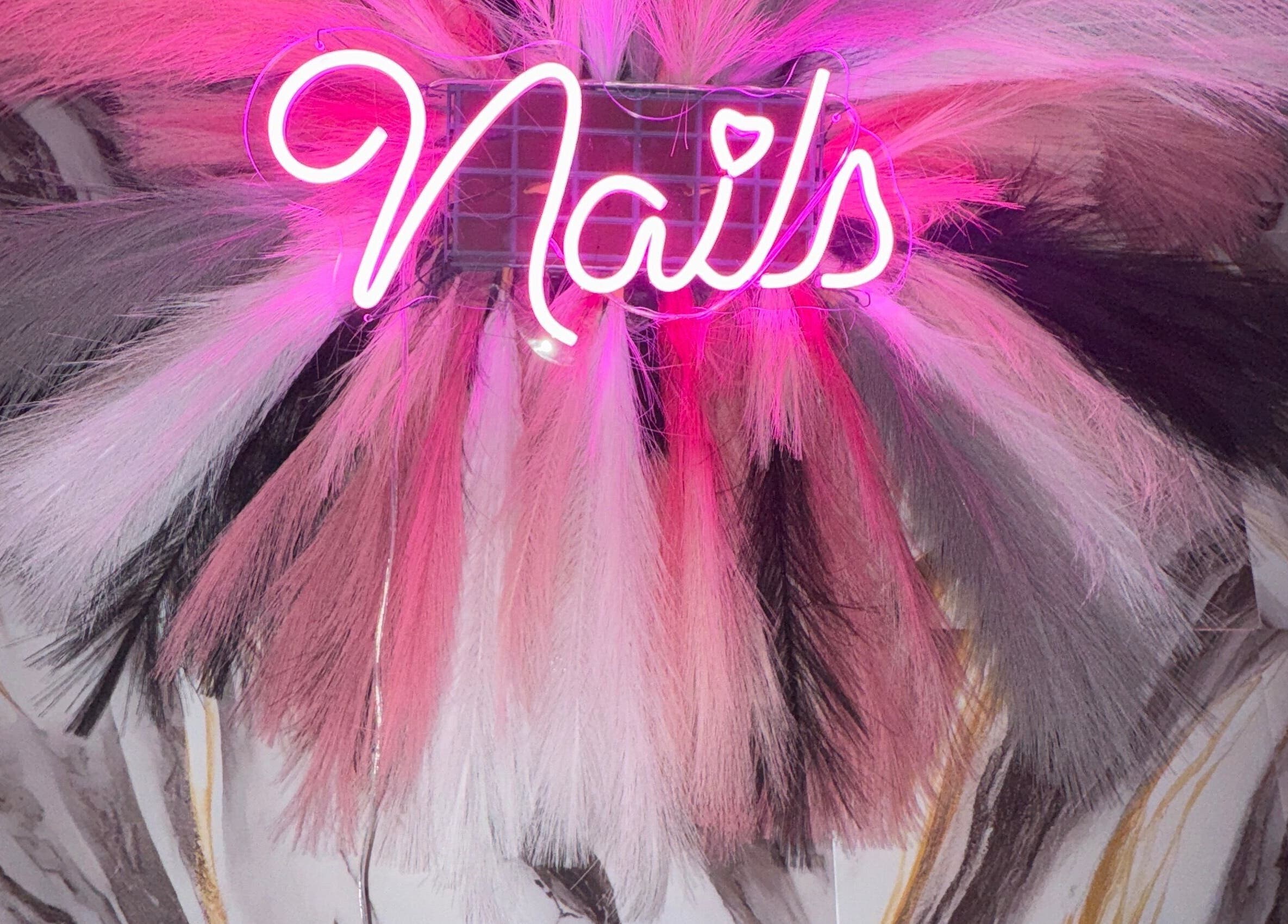 Vibrant neon 'Nails' sign at FHNAILSTUDIO in Ottawa, Ontario, CA with colorful feather backdrop.