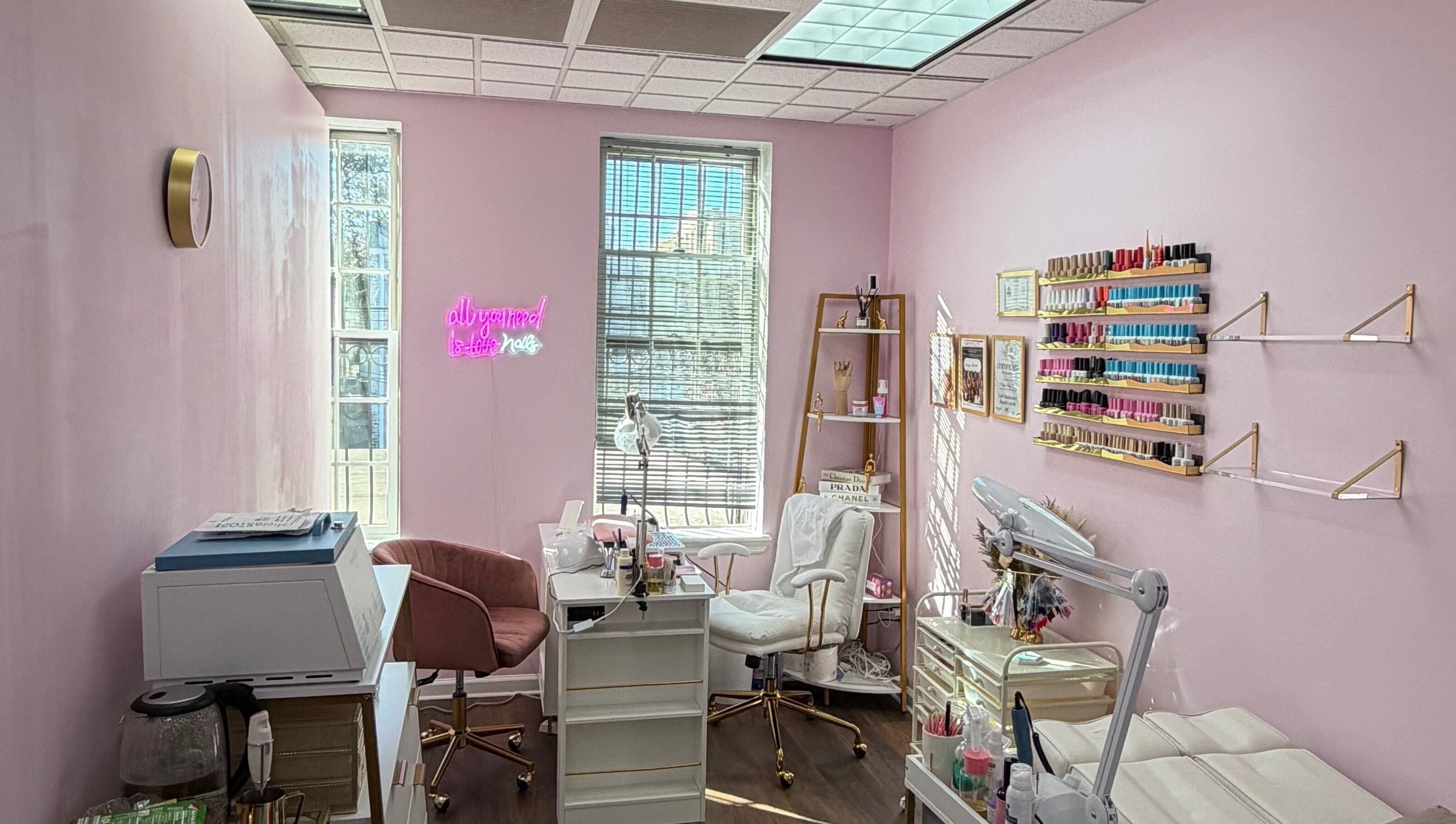 Сучасний салон HerynNails у Нью-Йорку з рожевими стінами, робочими місцями та полицями з лаком.