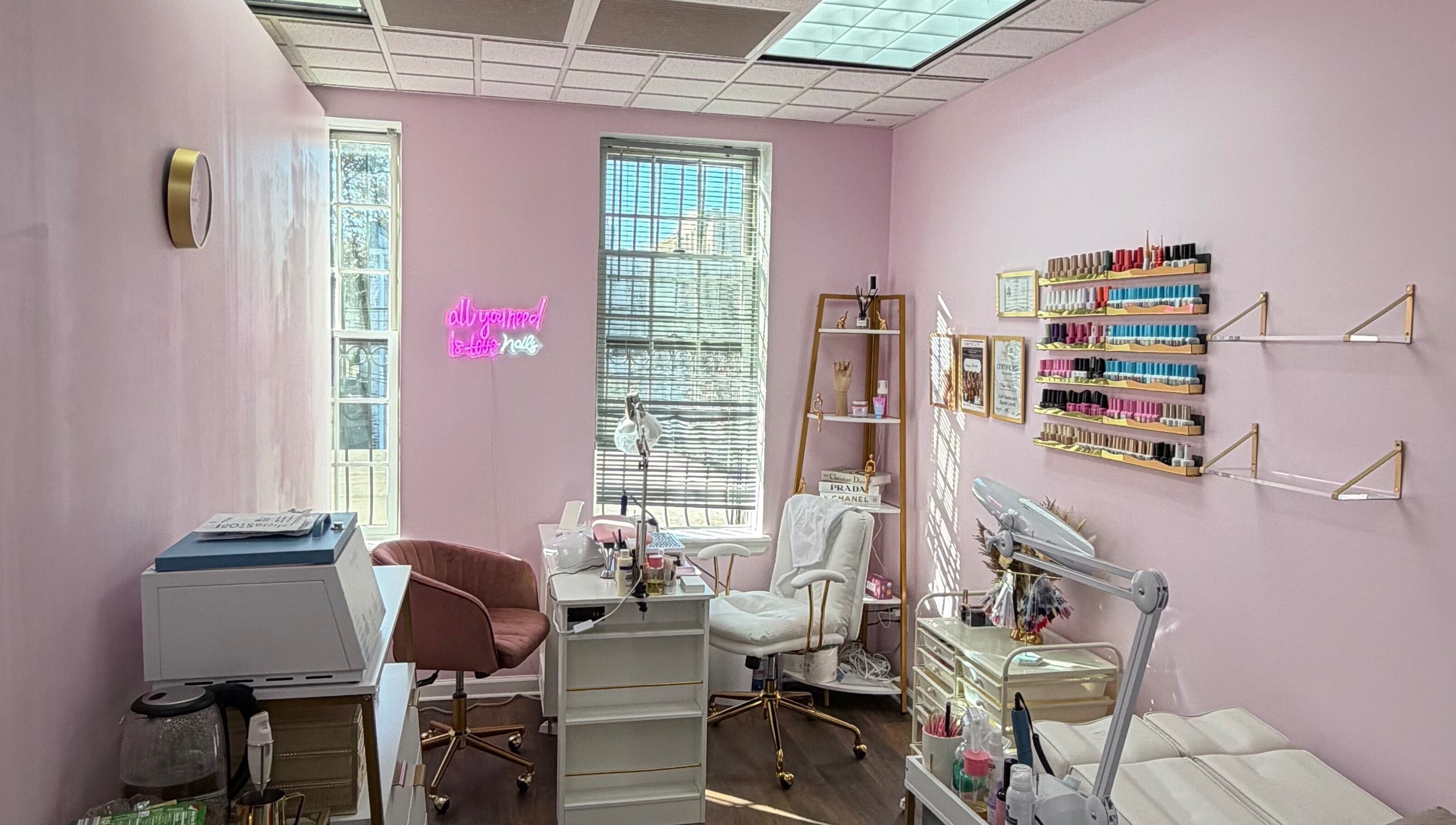 Сучасний салон HerynNails у Нью-Йорку з рожевими стінами, робочими місцями та полицями з лаком.