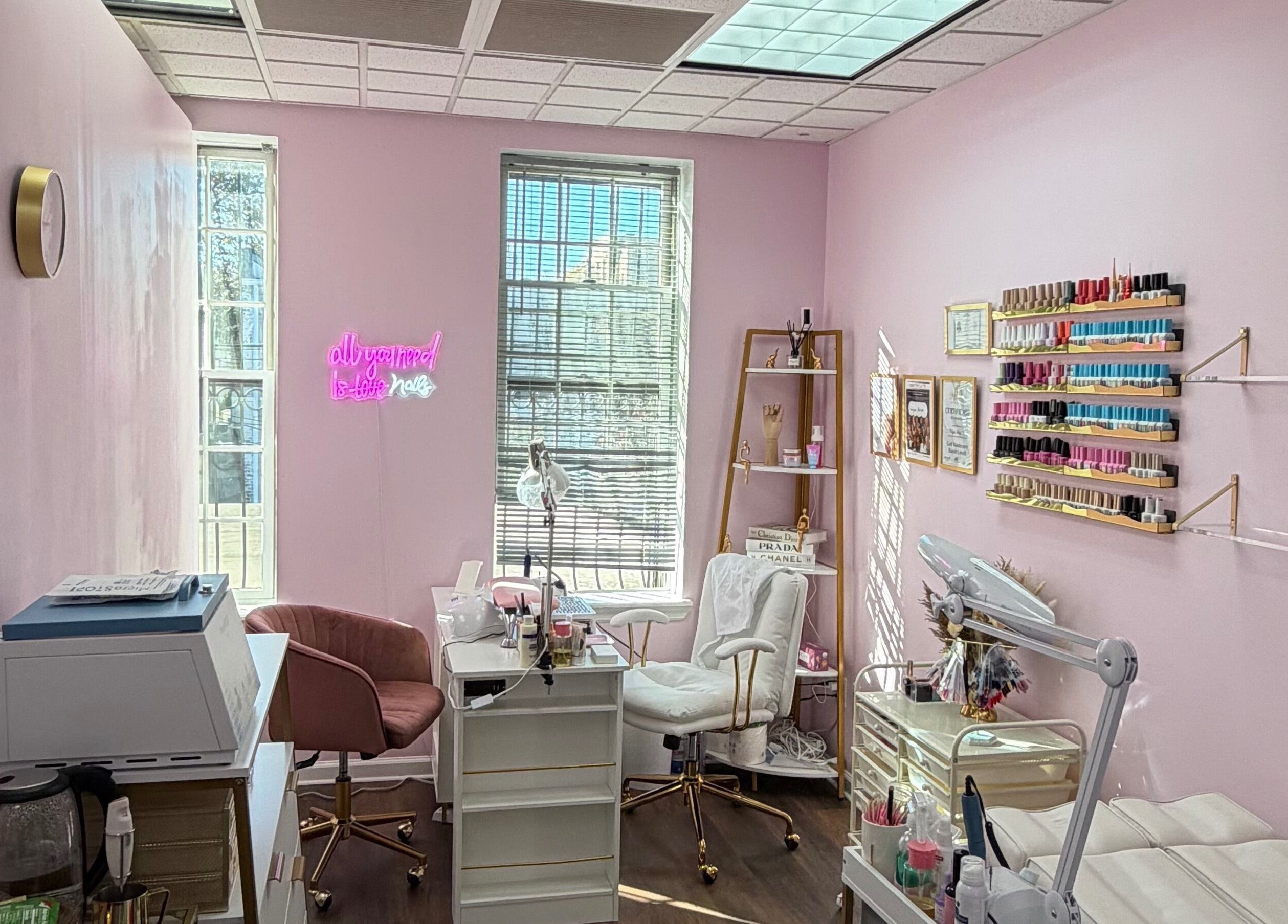 Сучасний салон HerynNails у Нью-Йорку з рожевими стінами, робочими місцями та полицями з лаком.